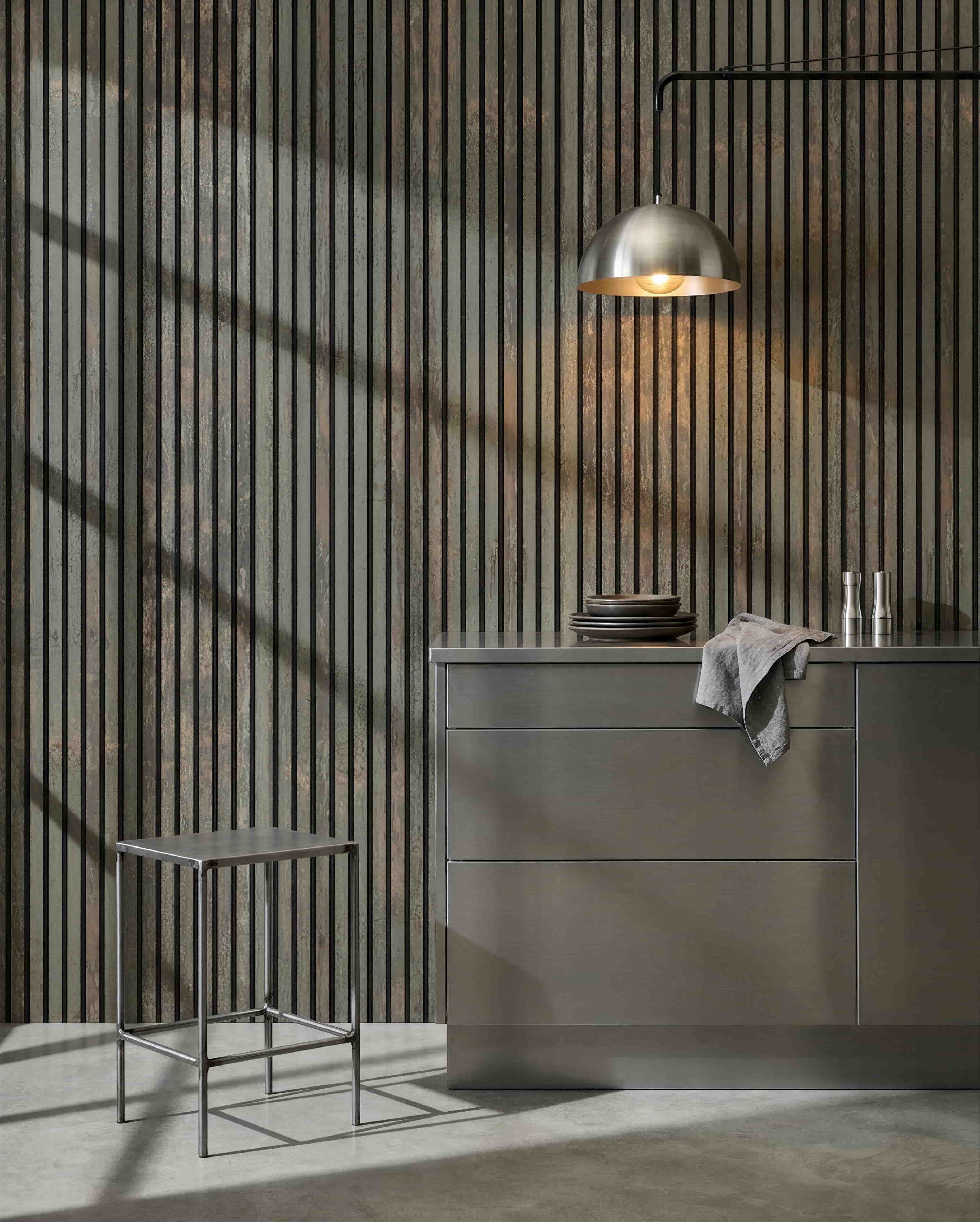 Cozinha minimalista com banco metálico, ilha grey e loiça, com um painel acústico de madeira WoodUpp Akupanel em feltro Oxide Grey/Black para controlo do som.