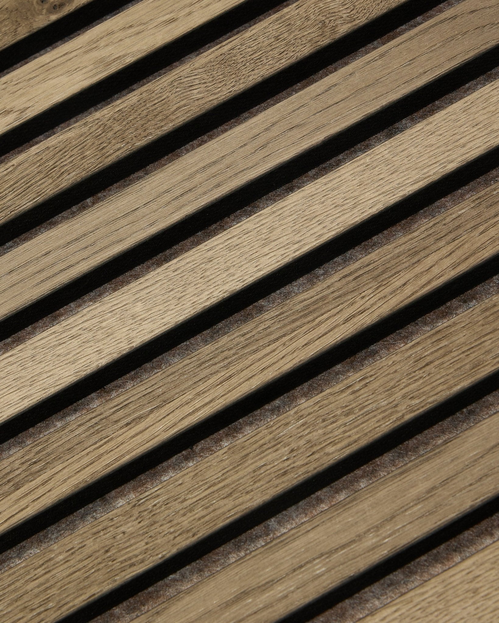 Plano aproximado do WoodUpp Tonal Akupanel Painel acústico em Grey Oak (240x60 cm), mostrando ripas diagonais uniformemente espaçadas, com veio de natural oak e design nórdico.