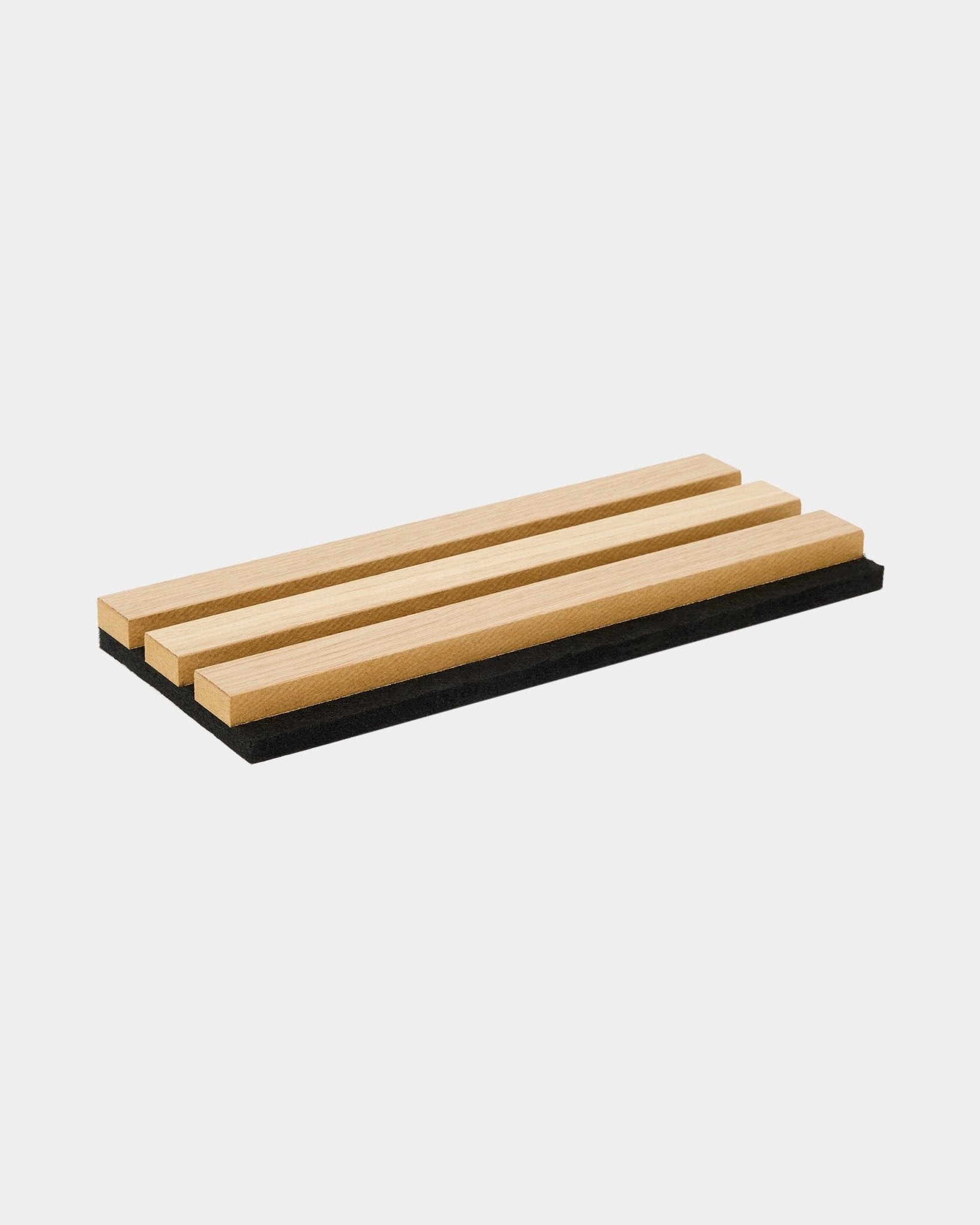 A bandeja de amostras WoodUpp Akupanel em Carvalho Clássico inclui três ripas acústicas de madeira sobre uma base de feltro black, evidenciando o design nórdico e o contraste entre materiais.