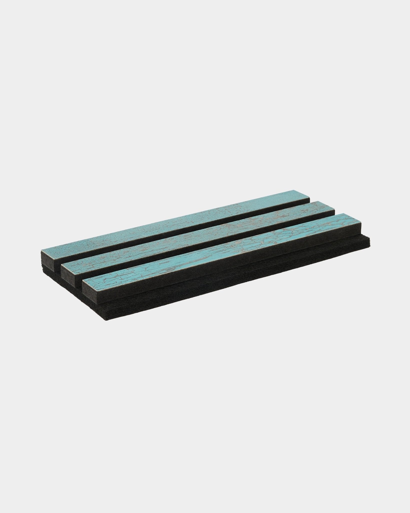 Três painéis de espuma Rebel Blue Oxide da WoodUpp estão empilhados em paralelo sobre uma superfície branca e limpa; foram concebidos como acessórios acústicos para interiores nórdicos.