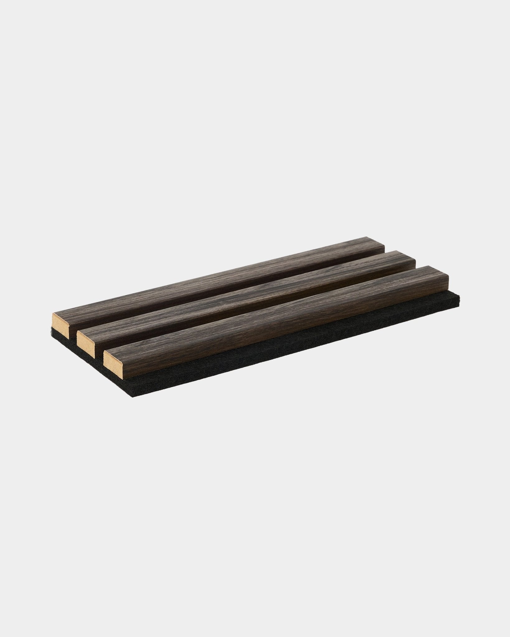 A amostra WoodUpp Essential em Black Oak é um acessório tipo base para panelas, retangular, com três ripas de madeira, pensado para complementar as coleções de painéis acústicos de madeira nórdicos.