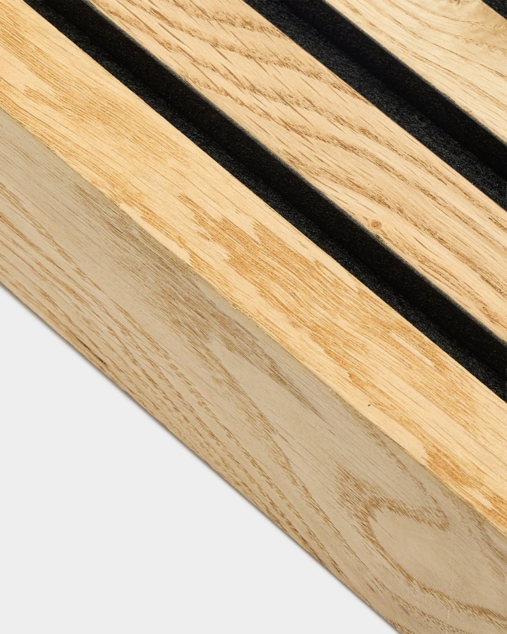 Vista de perto de uma lamela de extremidade WoodUpp Akupanel em Rustic Natural Oak, 6,7 cm, com ranhuras paralelas black e uma estrutura em MDF para instalação acústica na parede.