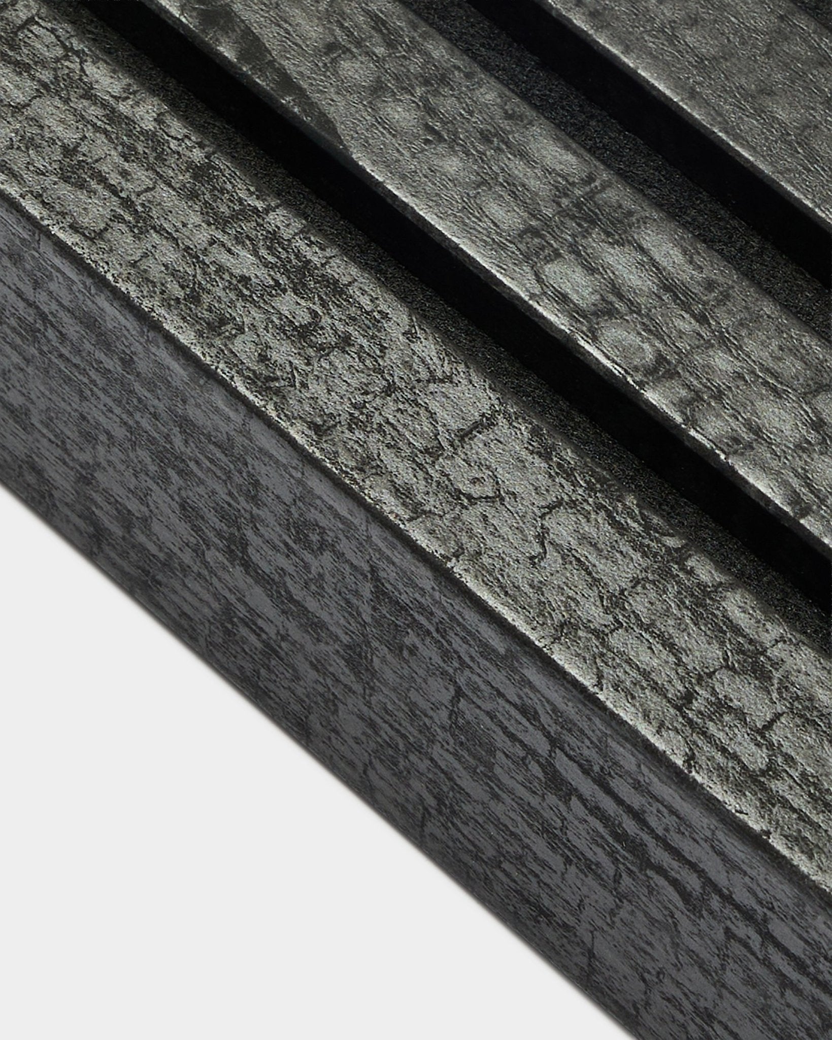 Imagem aproximada da lamela de extremidade WoodUpp Akupanel em Charcoal, com 6,7 cm de largura, com ripas acústicas paralelas e textura de veio da madeira distinta.