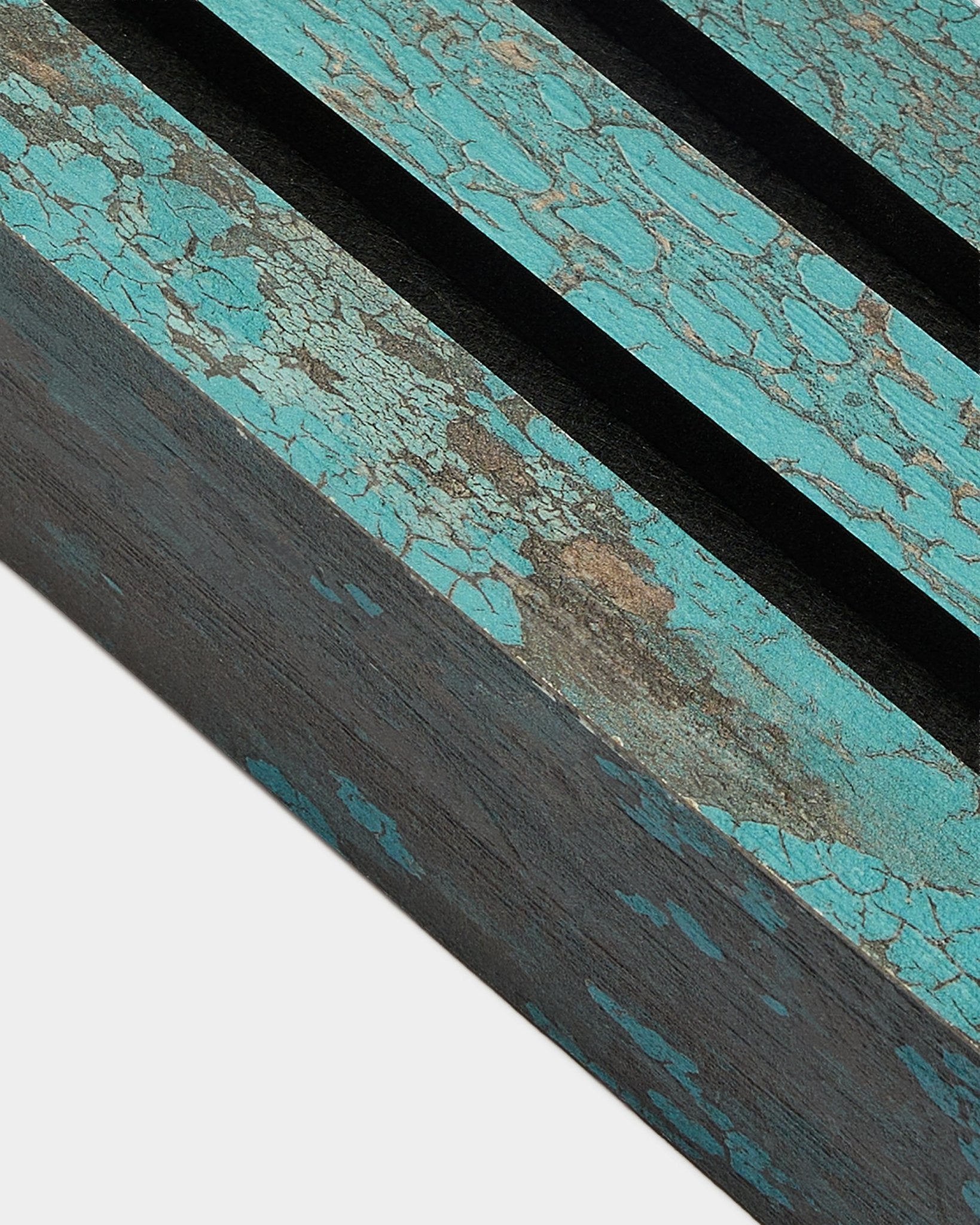 Vista aproximada da lamela final WoodUpp Akupanel em Oxide Blue, com 6,7 cm de largura, com pintura azul estalada e ranhuras black numa superfície rústica Painel acústico.