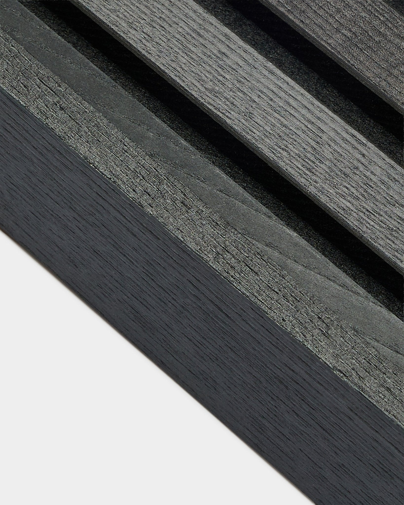 Pormenor da lamela de extremidade WoodUpp Akupanel em Freixo Black (6,7 cm), mostrando o veio da madeira em cinzento-escuro sobre uma base clara, concebida para instalações nórdicas Painel acústico.