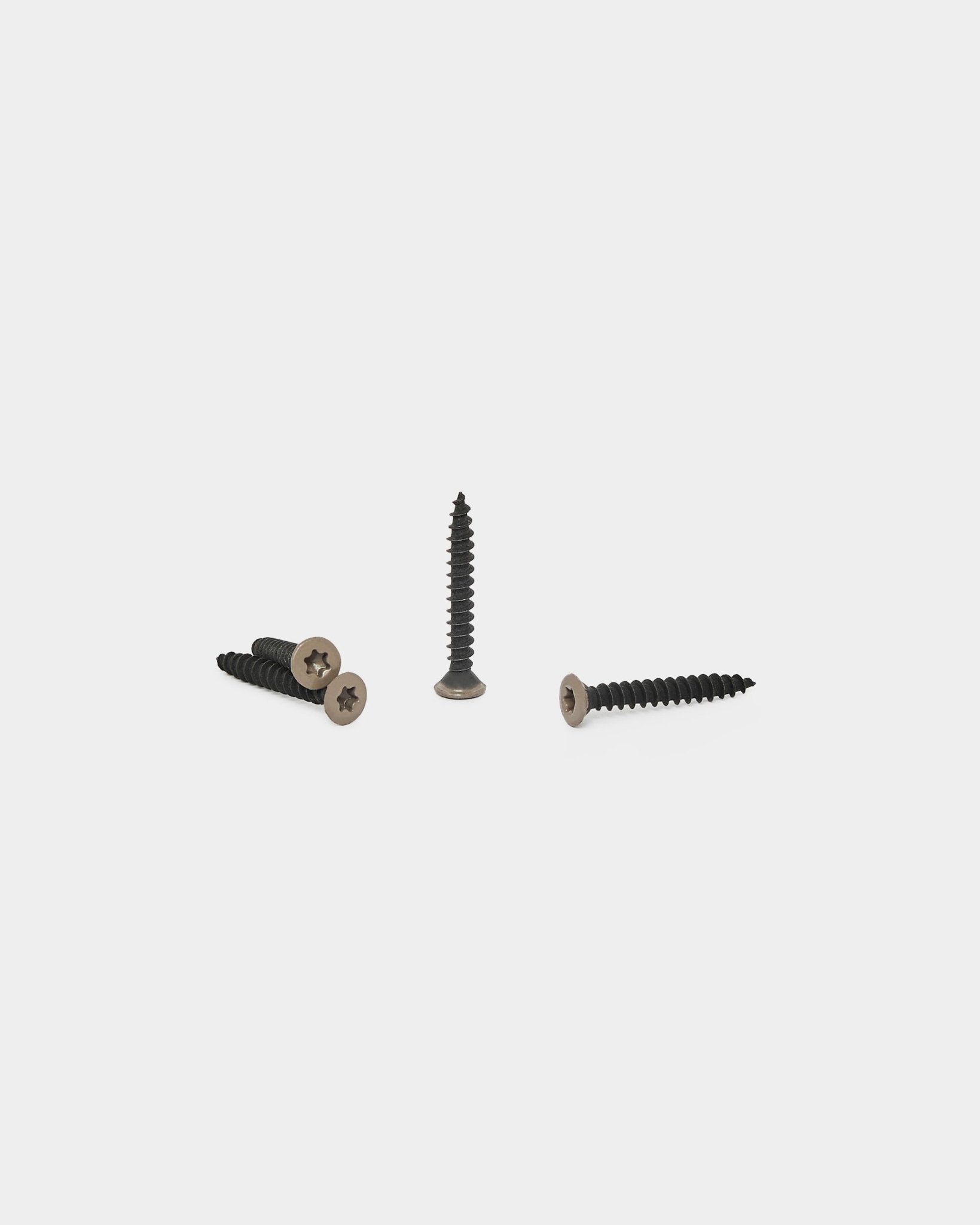 Três parafusos warm grey para painéis acústicos WoodUpp estão dispostos sobre um fundo branco, um na vertical e dois deitados com a cabeça visível.