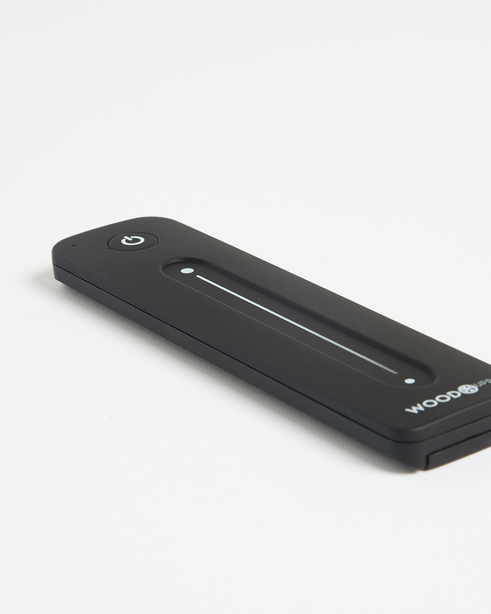 Comando WoodUpp Lumi para fitas LED em black, com botão de ligar/desligar, compatível com Philips Hue, apresentado sobre uma superfície branca.