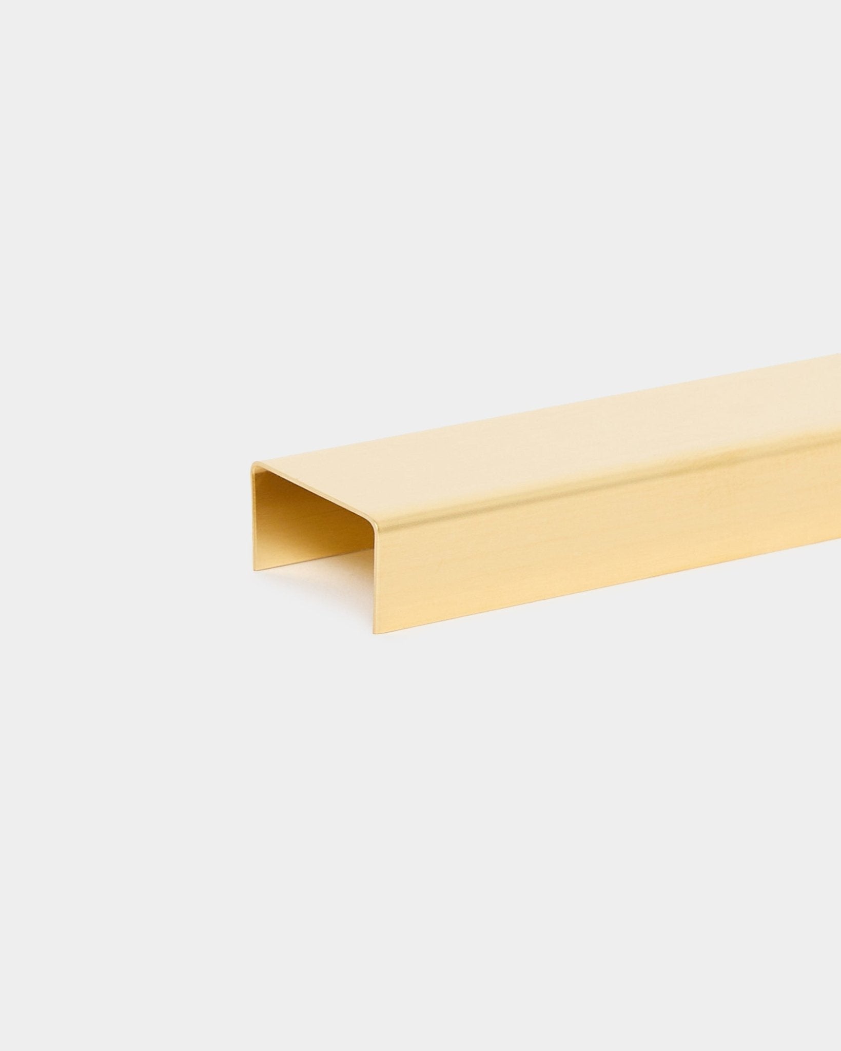 O Liva | Cover em brass, 60 cm, da WoodUpp, é um acessório de remate metálico em forma de U para painéis acústicos Akupanel, apresentado sobre um fundo liso cinzento-claro.