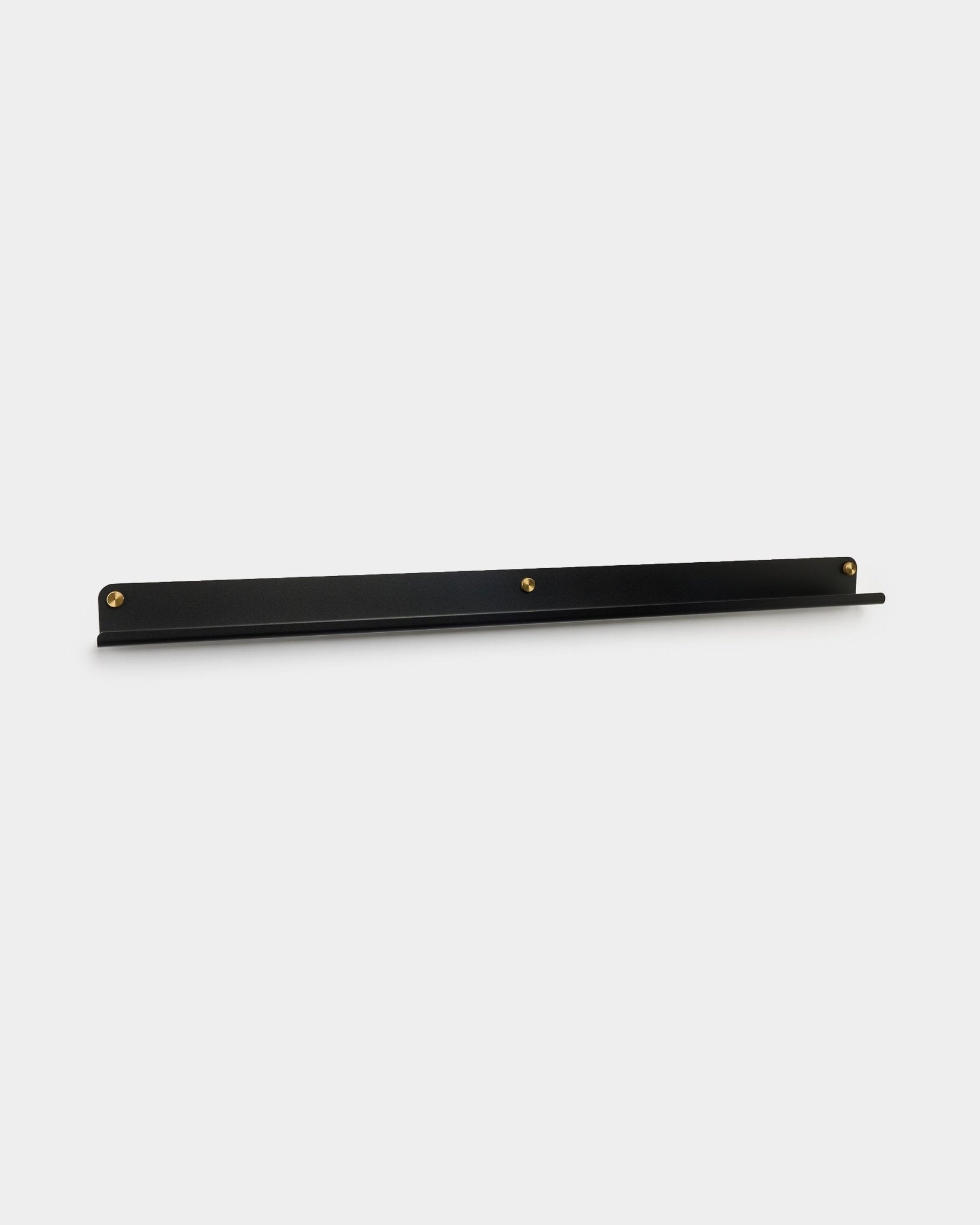 A Narrow Shelf Norr em black da WoodUpp, 115,9 cm, montada na parede com três parafusos de aperto manual brass, apresentada sobre um fundo branco liso.