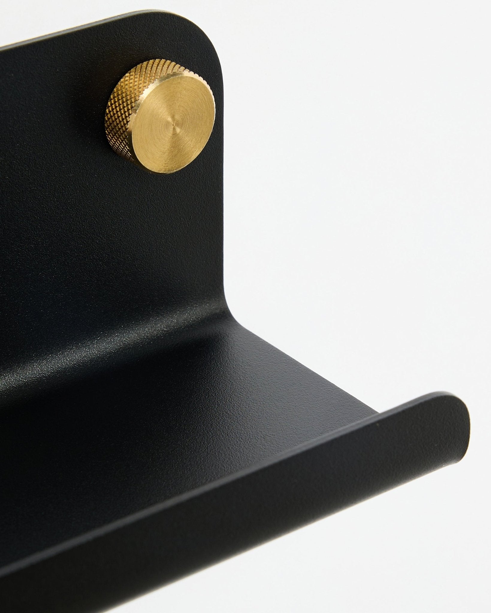 Pormenor da prateleira estreita WoodUpp Norr, 35,9 cm, black steel com bordo curvo e botão dourado, apresentada sobre um fundo branco.