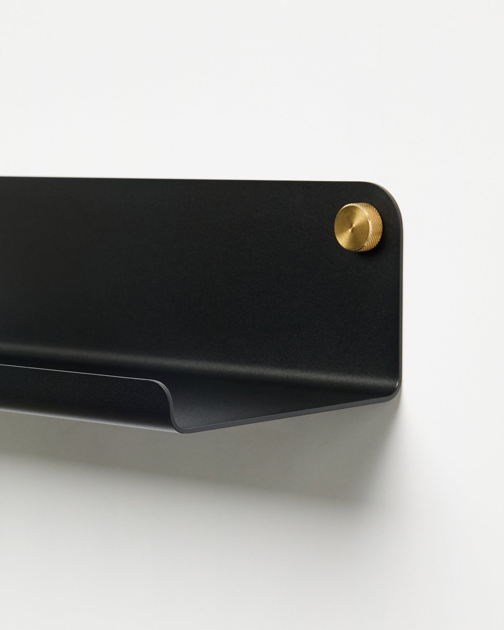 Pormenor do acessório Prateleira Larga WoodUpp Norr (51,9 cm) em metal black com revestimento a pó e parafuso dourado, colocado sobre um fundo branco liso.