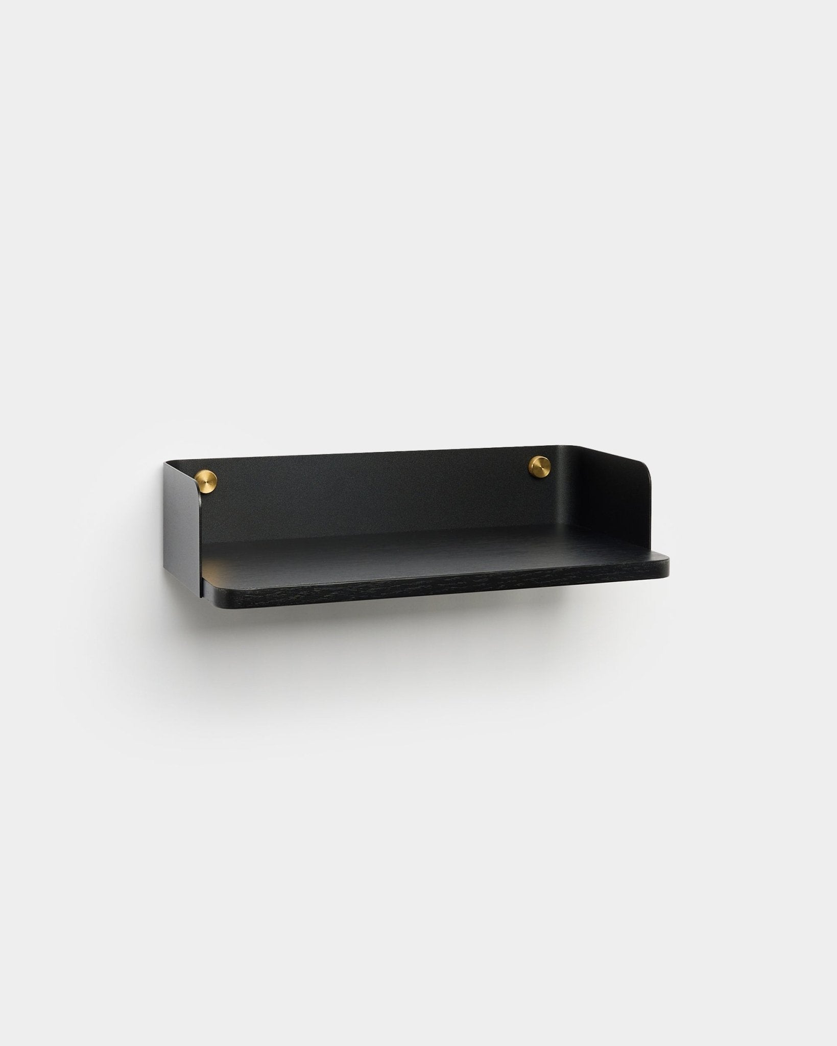 A prateleira Linn da WoodUpp, com um acabamento minimalista em black e parafusos de montagem em brass, está montada numa parede cinzento-claro, a complementar um design de interiores nórdico.