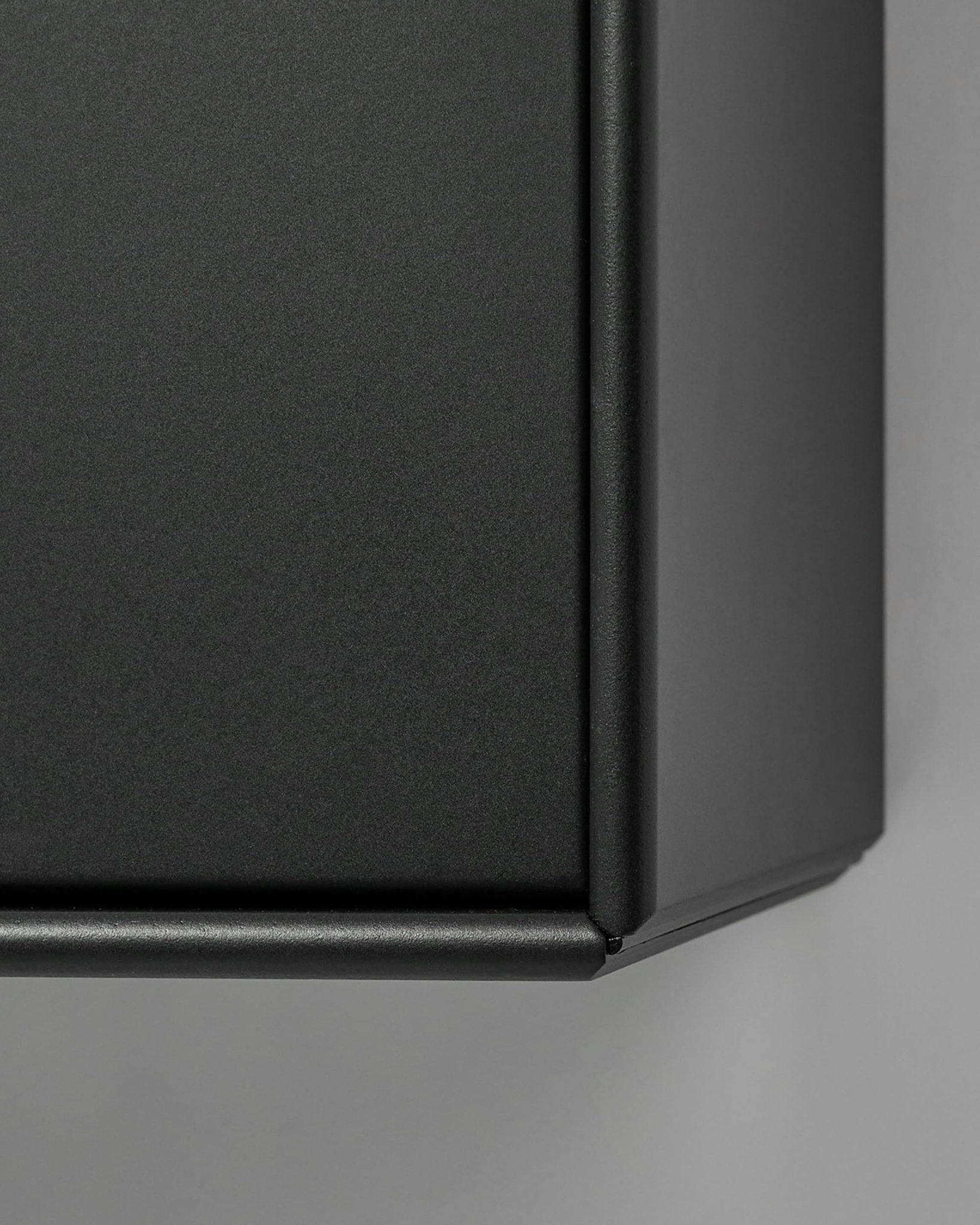 Mesa de televisão Arka da WoodUpp em metal preto mate, apresentada em grande plano contra um fundo cinzento claro. O design nórdico complementa as coleções de painéis acústicos em madeira.