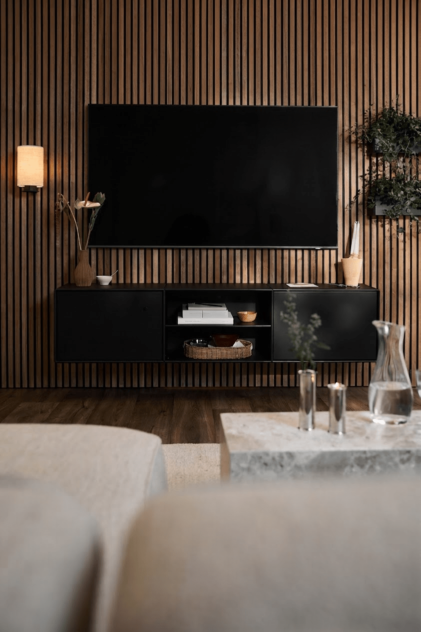 Sala de estar moderna com a consola de TV WoodUpp Arka em preto, parede com ripas Akupanel, detalhes minimalistas e um sofá claro com mesa de centro.