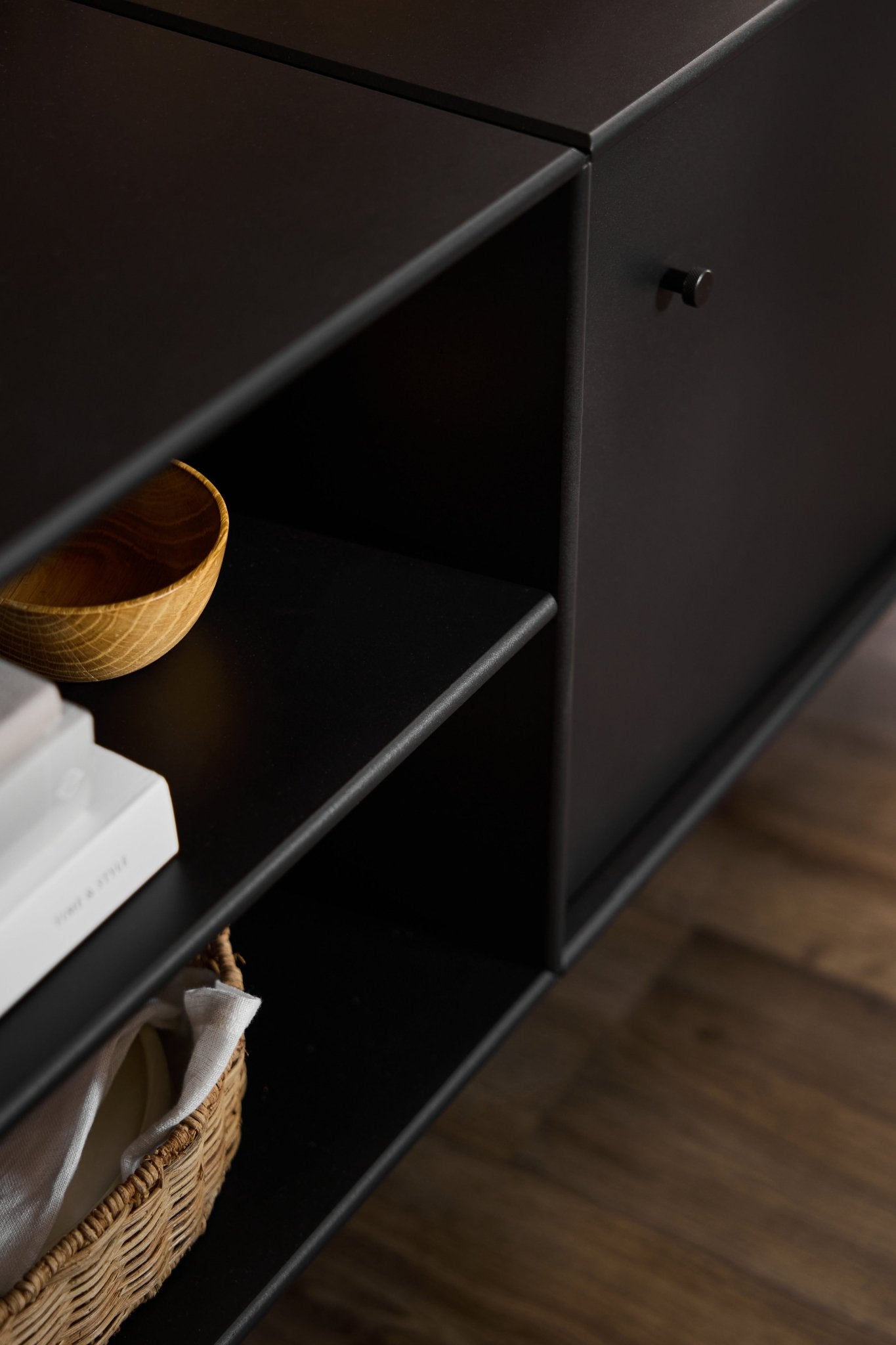 Móvel de televisão «Black Arka» da WoodUpp, com um estilo minimalista, concebido para a organização dos cabos e para arrumação, colocado sobre um pavimento de madeira.