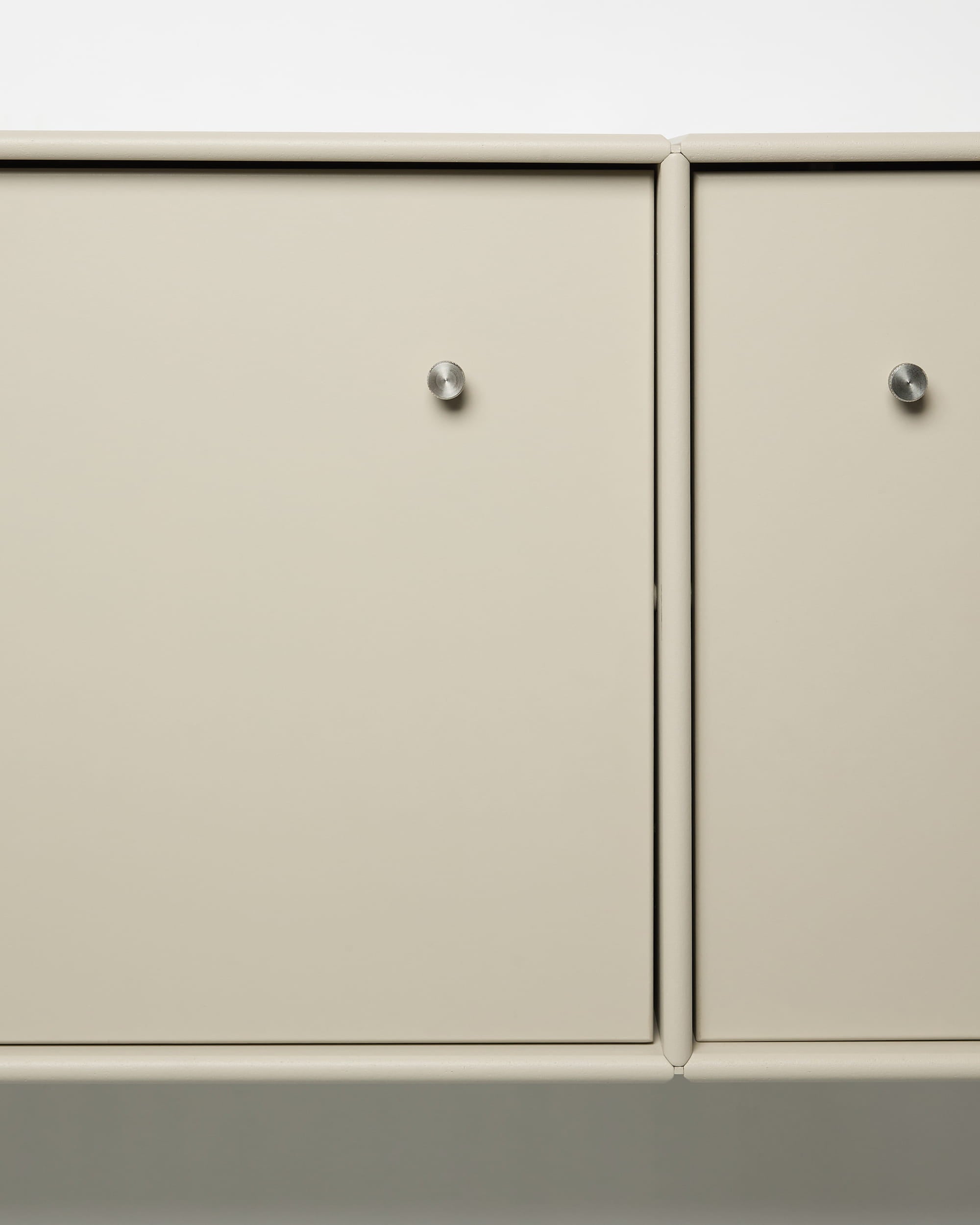 Móvel de televisão Arka da WoodUpp, com portas de metal em bege, puxadores redondos prateados, design modular e sistema integrado de organização de cabos, ideal para interiores de estilo nórdico.