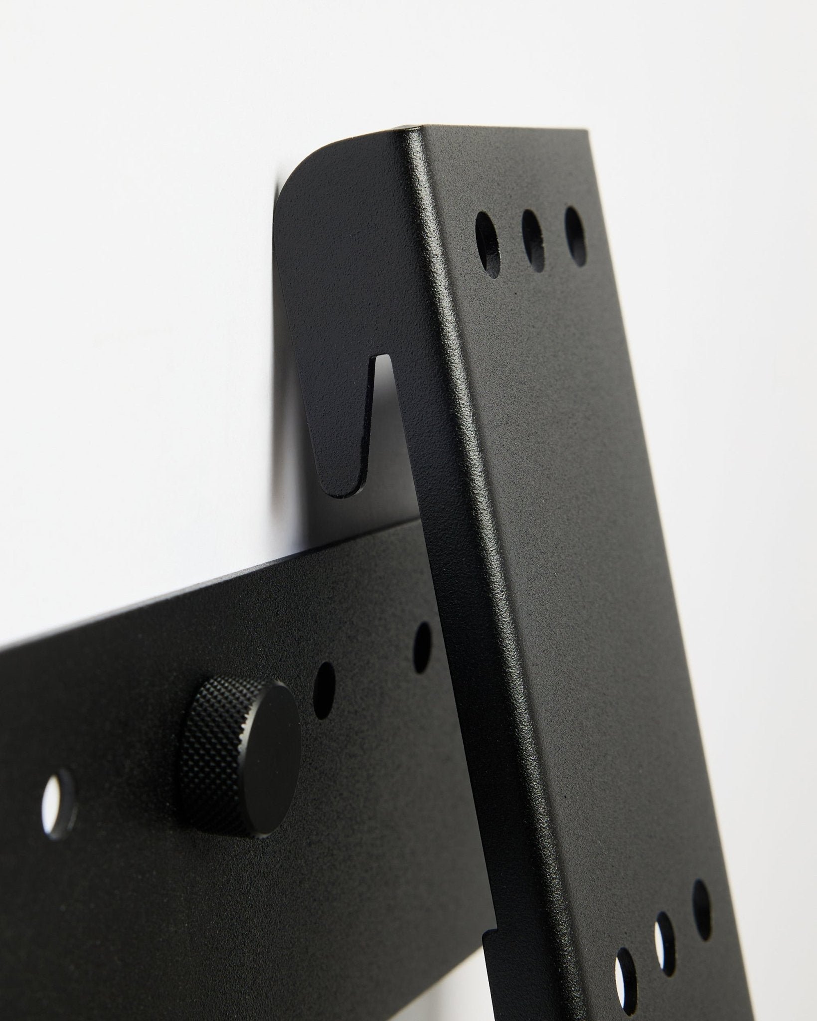 Suporte para TV WoodUpp Fjell (large), um suporte metálico black para TVs de 85 polegadas com VESA 600x400, montado numa parede branca.