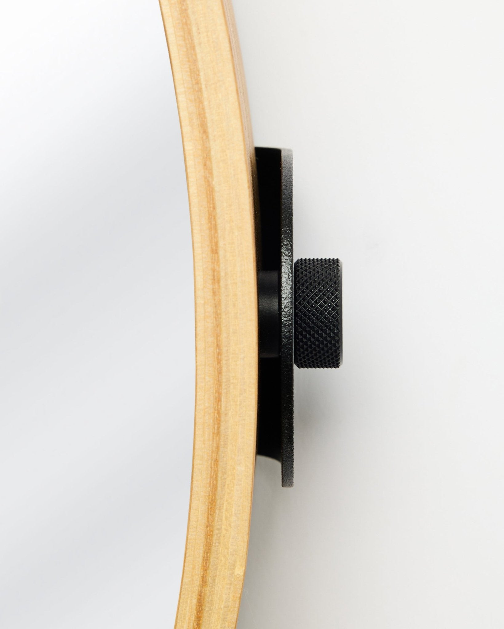 Vista lateral em grande plano do Linn | Mirror da WoodUpp em Natural Oak, com moldura redonda em carvalho e botão metálico black, um acessório para painéis acústicos de madeira.