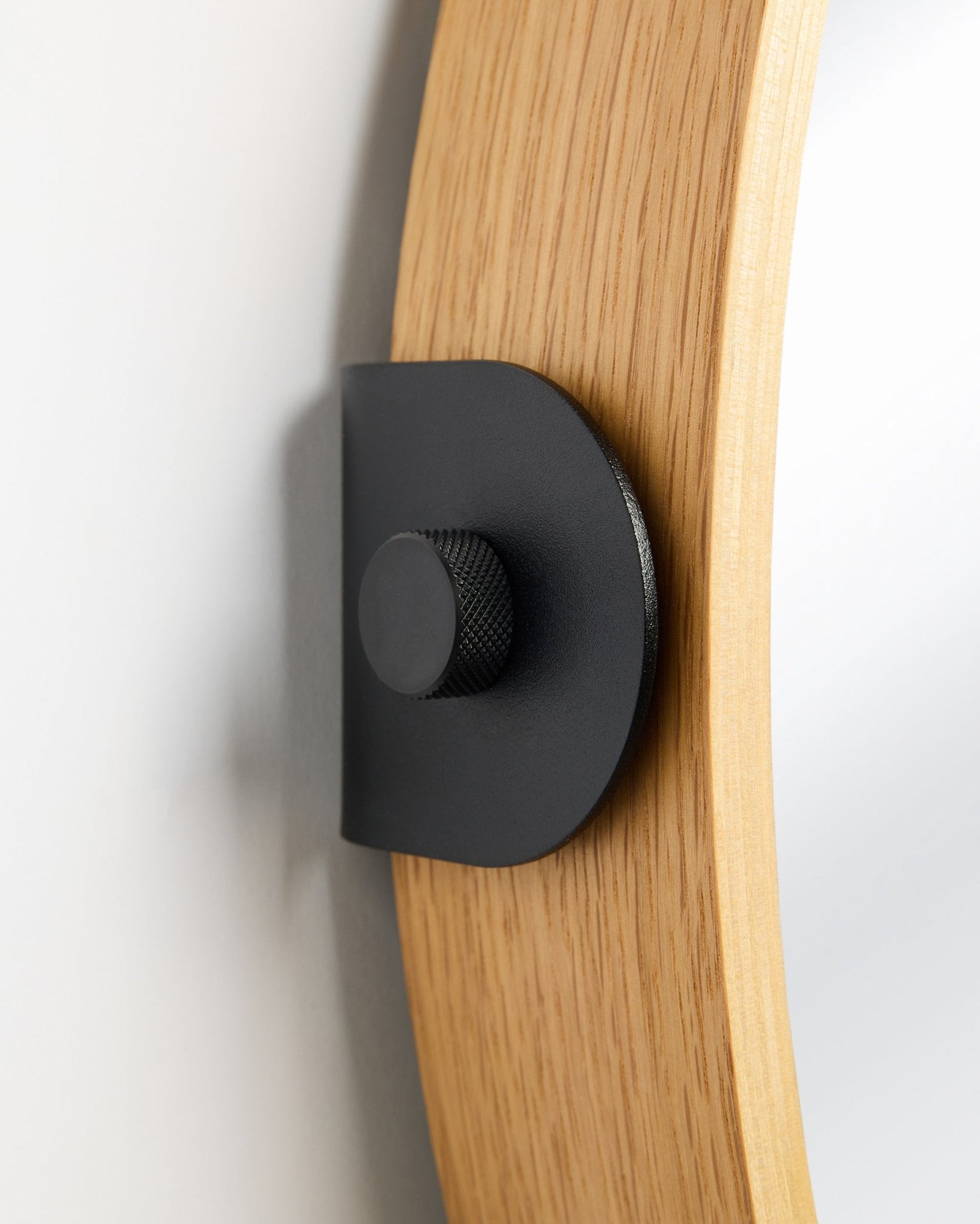 Pormenor do espelho Linn da WoodUpp em Natural Oak, um Painel acústico montado na parede com um suporte metálico black e um botão redondo.