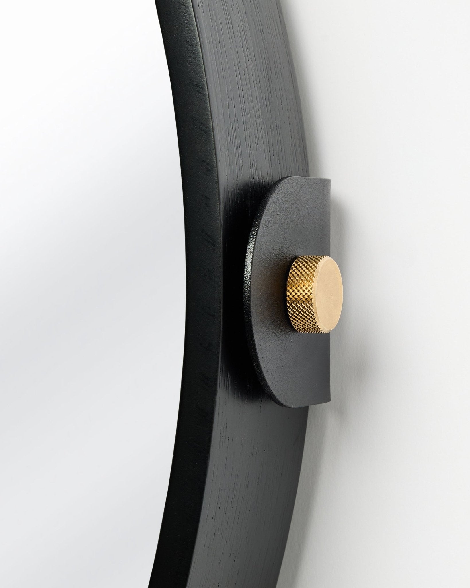 Detalhe do Linn | Mirror / Black Oak Painel acústico da WoodUpp, montado na parede com um botão dourado e inclinação ajustável.