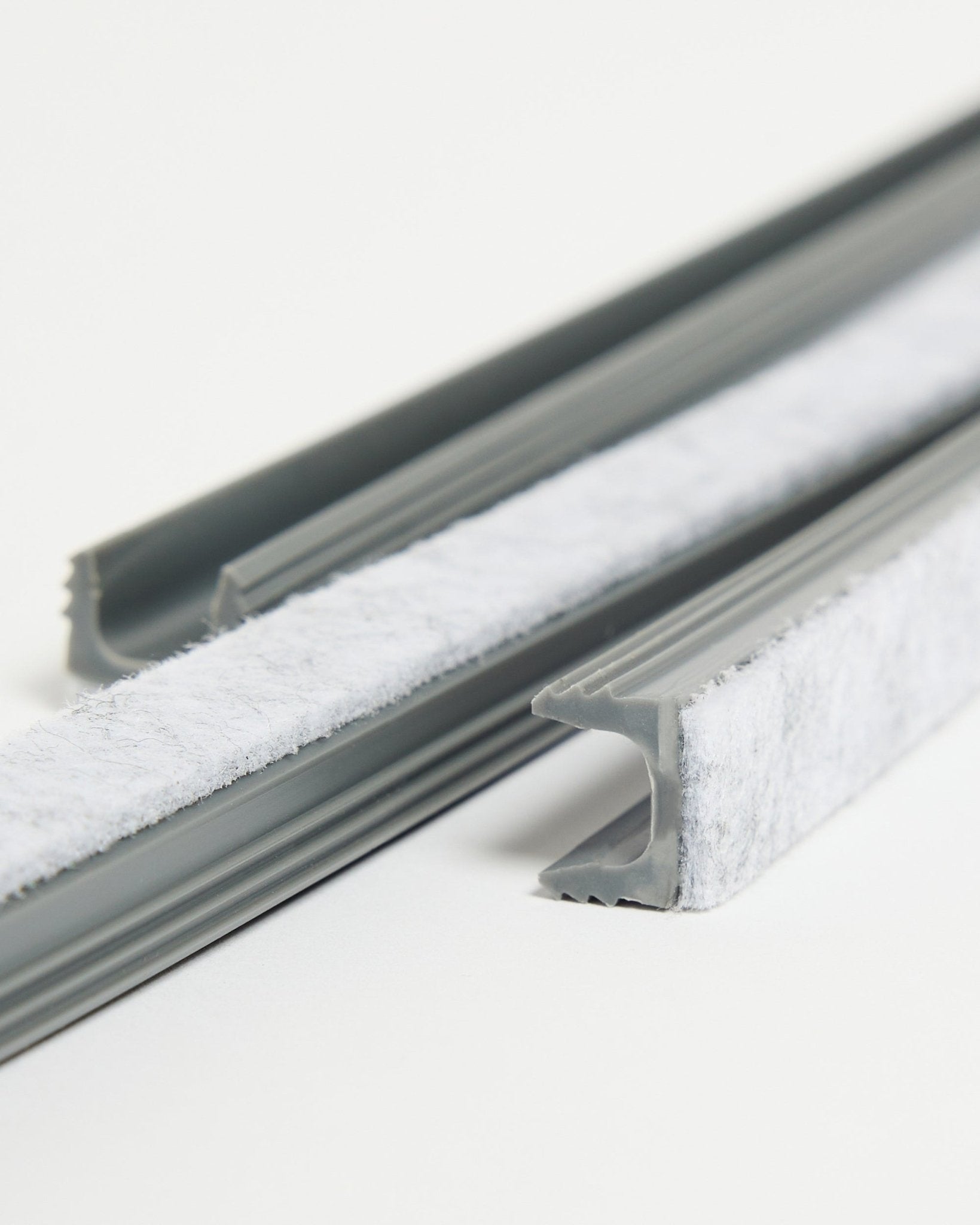 Três Dupps Pop-on Cable Covers cinzentas da WoodUpp, com vedante branco e canais flexíveis em TPV, colocadas sobre uma superfície branca.