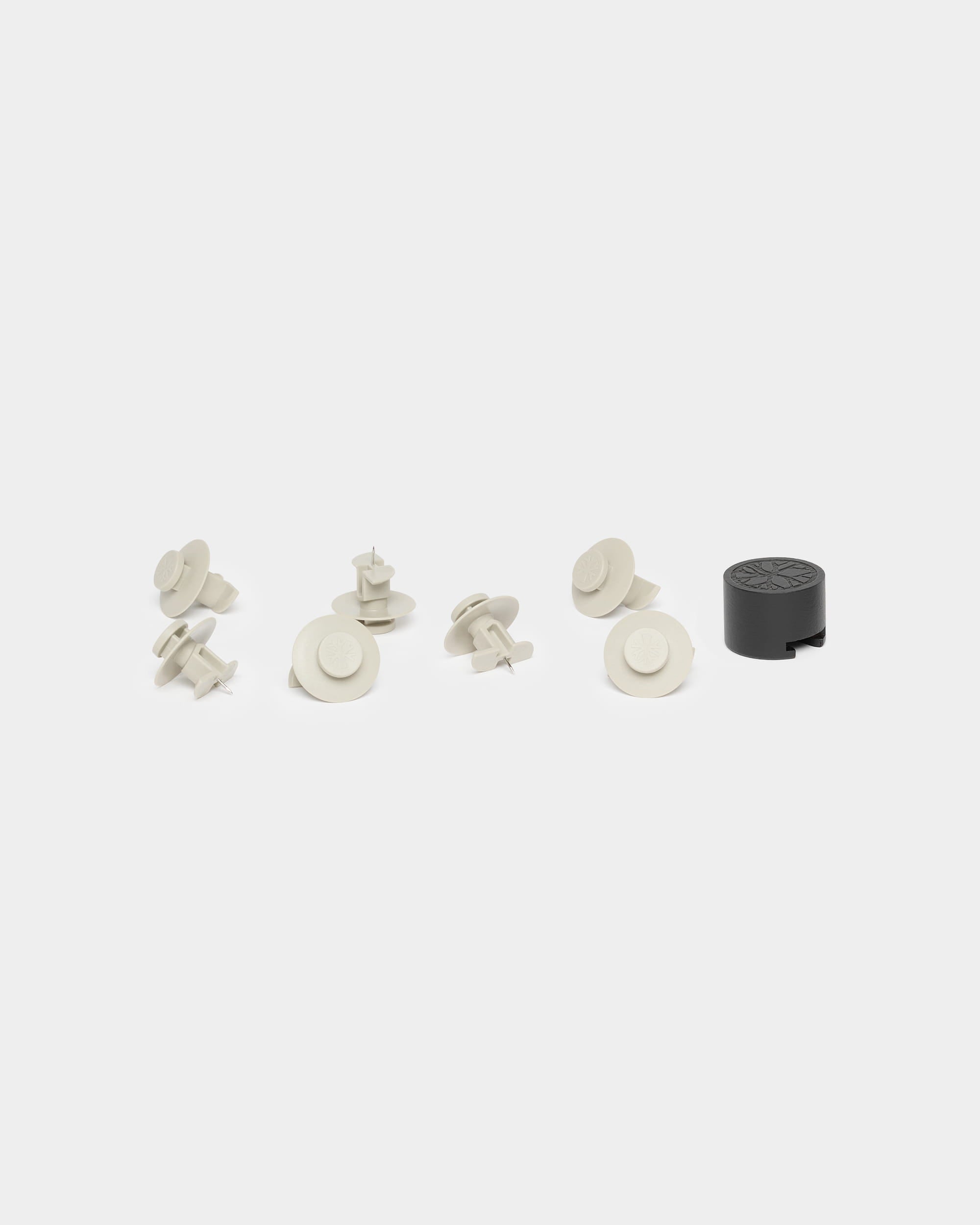 Sete fixadores bege e uma ferramenta de instalação preta para o WoodUpp Akupanel, apresentados sobre um fundo branco.