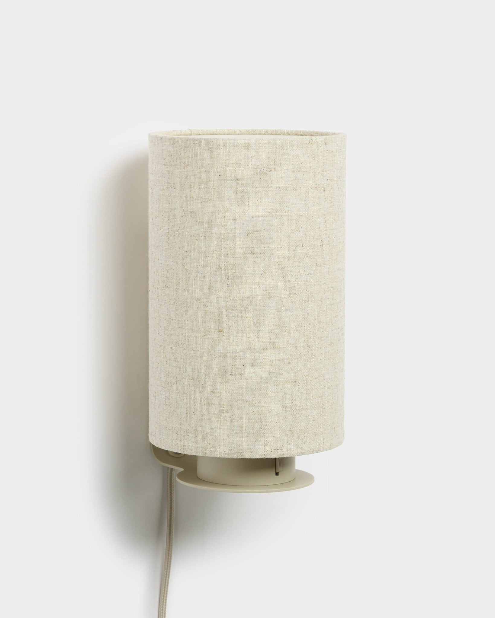 Feya | Wall Lamp da WoodUpp, com um abajur cilíndrico em linho-algodão e cabo branco visível, acabamento beige, concebido para complementar painéis acústicos em madeira.