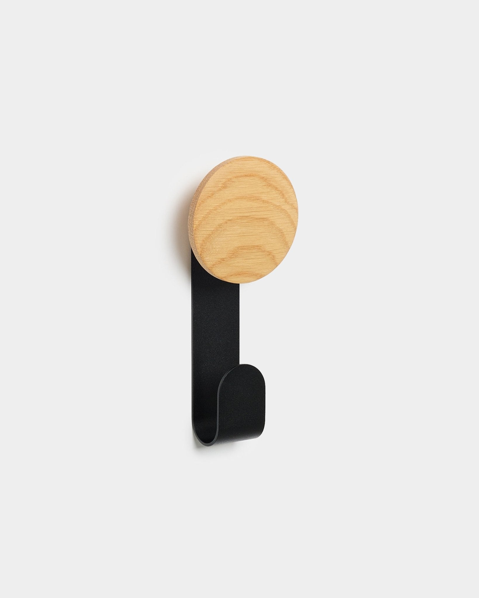 O cabide Linn Vertical da WoodUpp, com topo redondo em natural oak e gancho metálico em black, foi concebido para pendurar acessórios nos painéis acústicos de madeira Akupanel Nordic.