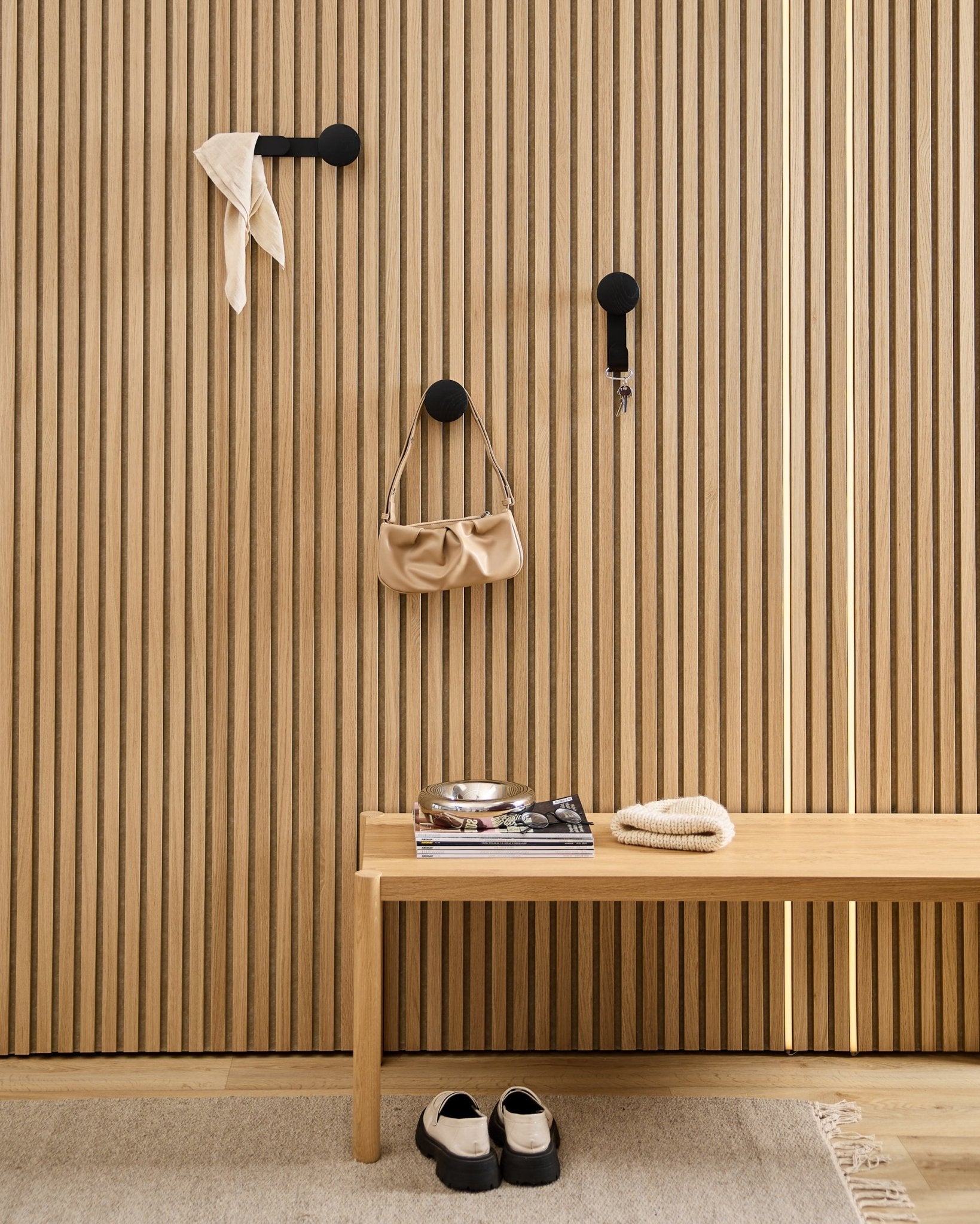 Entrada minimalista com o cabide WoodUpp Linn Horizontal em Black Oak, com ganchos black, banco de madeira, sapatos, livros e um prato. Estilo nórdico.