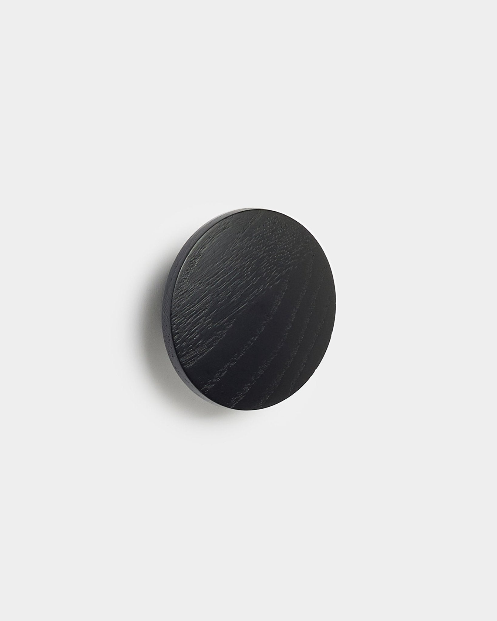 O Linn | Single Hanger em black oak da WoodUpp, um acessório redondo para painéis acústicos Akupanel, apresentado sobre um fundo branco liso.