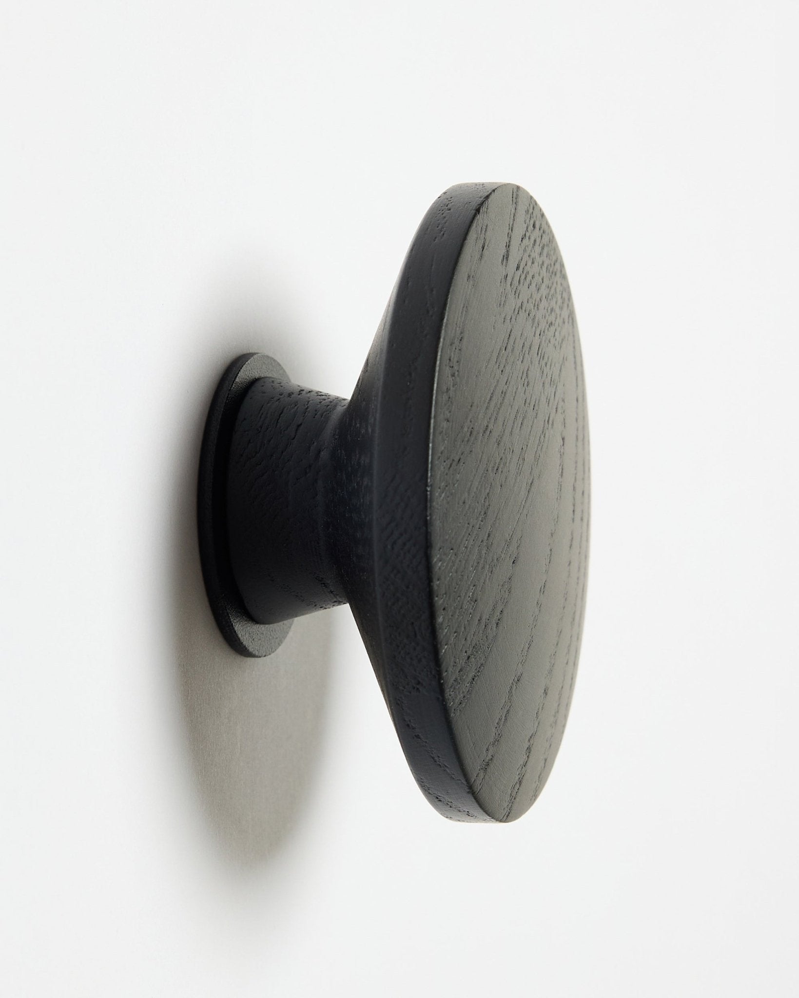 Um Linn | Single Hanger redondo black oak da WoodUpp, concebido como acessório para painéis acústicos de madeira Akupanel, montado numa superfície branca com uma sombra suave à esquerda.
