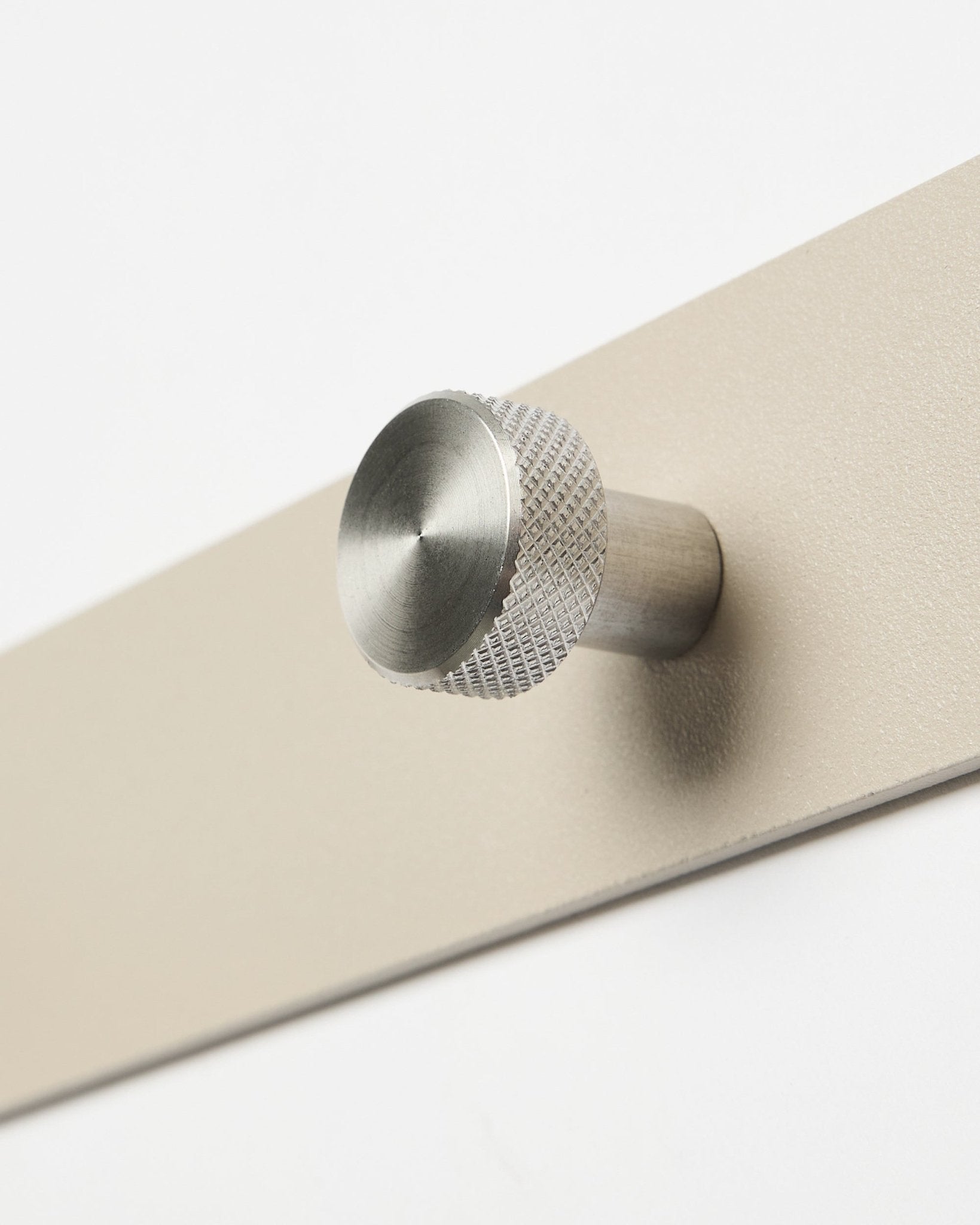 Cabideiro de parede Norr em beige e steel inoxidável da WoodUpp, acessório para a coleção Akupanel, mostrado em plano aproximado sobre fundo branco.