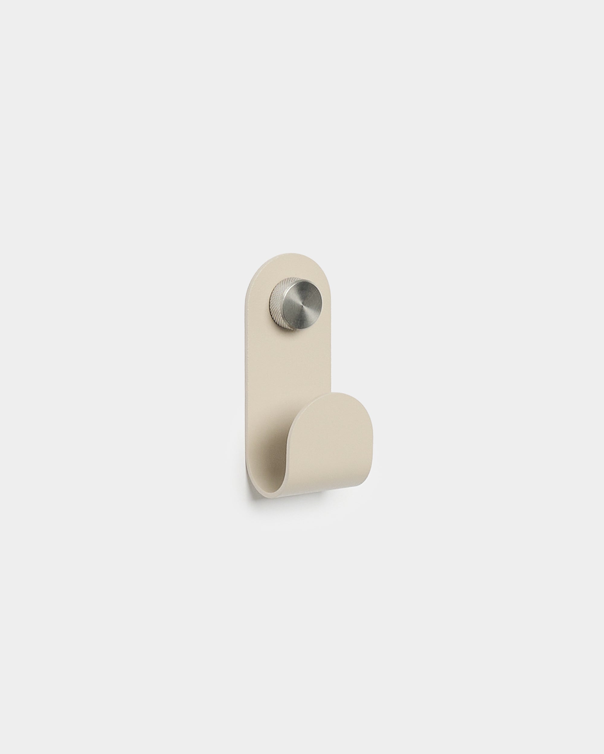 WoodUpp Norr Single Hanger em beige, com uma forma curva minimalista e acabamento em metal escovado, concebido como acessório para ganchos de parede Akupanel compactos.