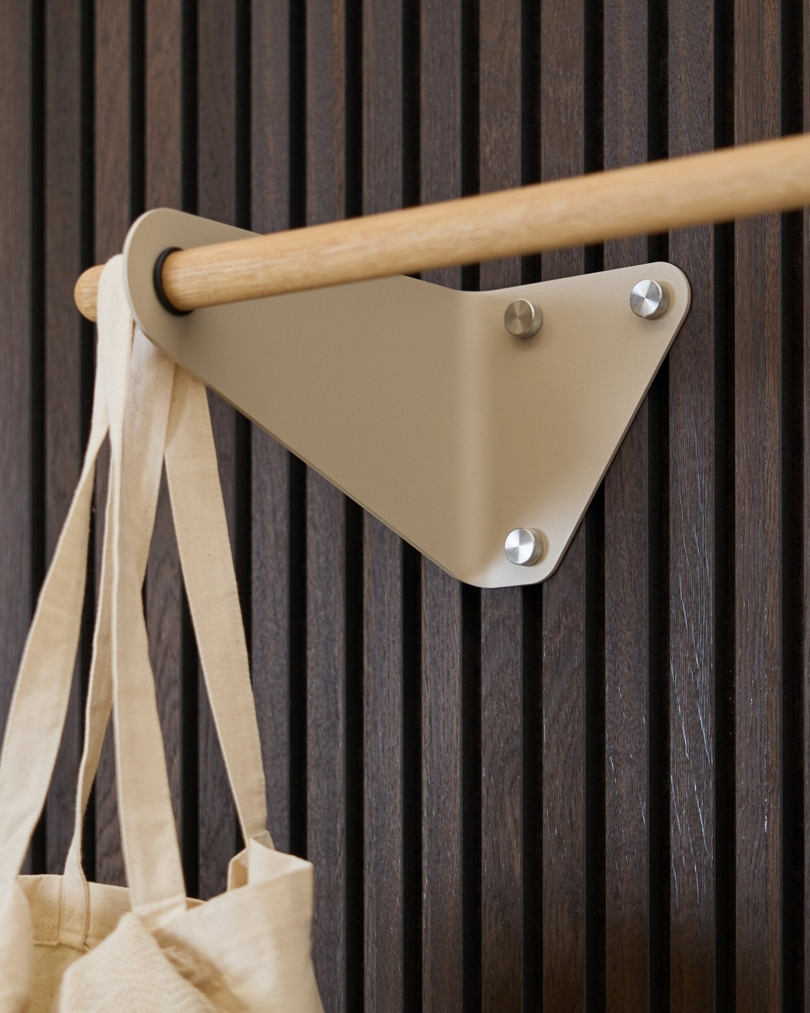 Cabide WoodUpp Linn em Beige (115,9 cm) montado num Akupanel Painel acústico, com um saco em tecido creme pendurado no lado esquerdo.