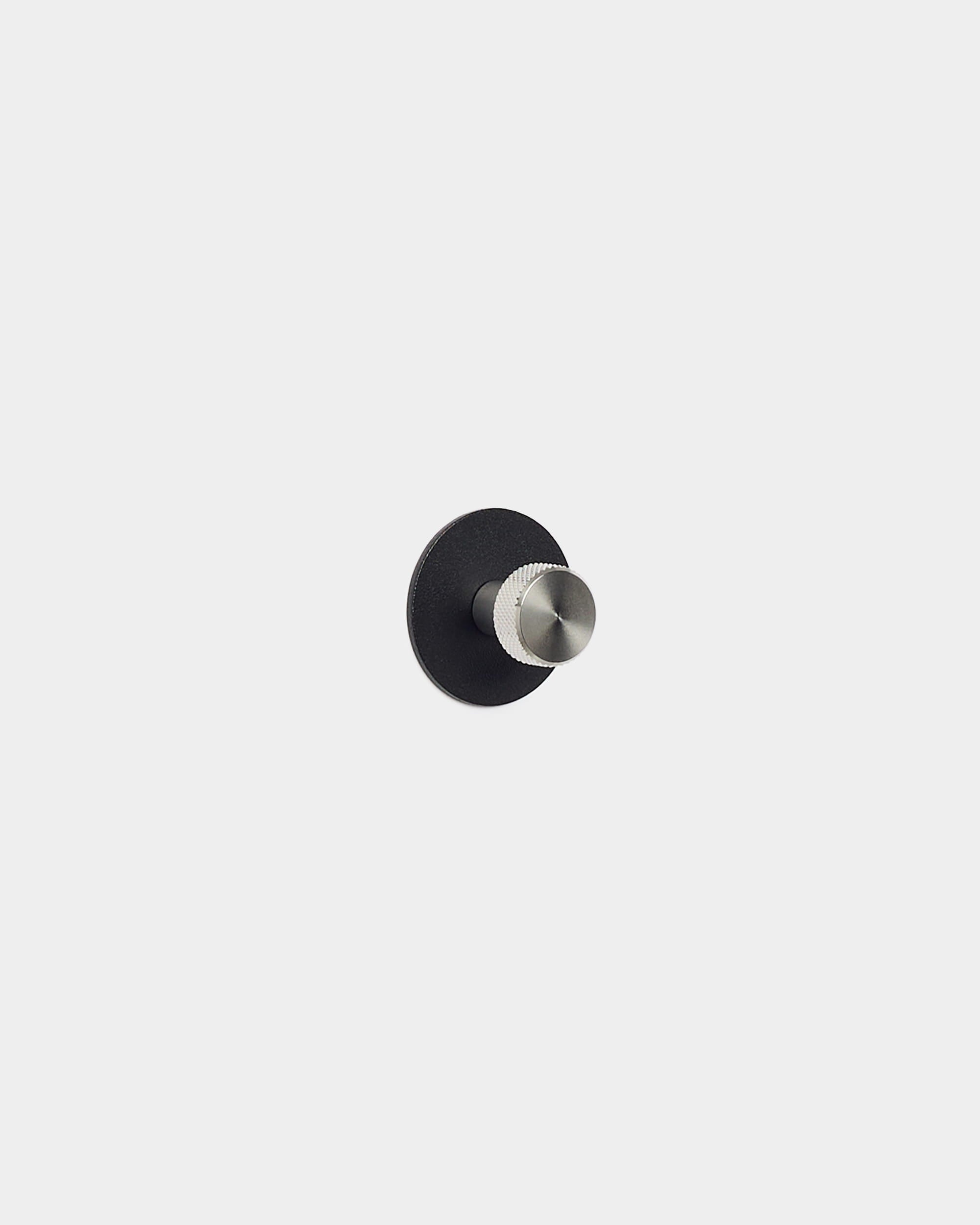 O gancho de parede Norr da WoodUpp tem uma base redonda em black e pino prateado, pensado como acessório para painéis acústicos Akupanel — enquadra-se bem em espaços minimalistas e nórdicos.