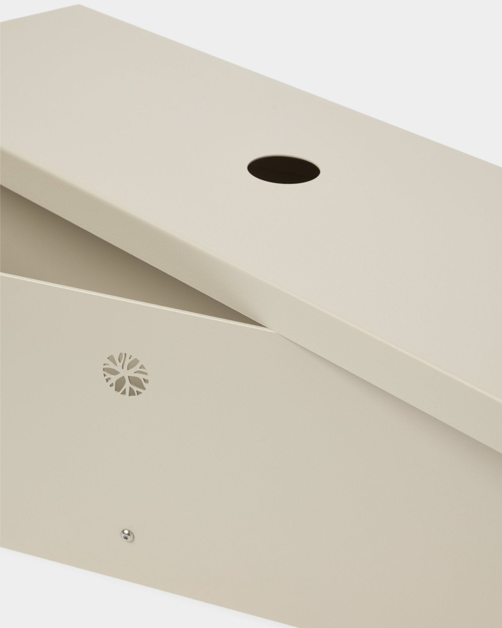 O Nell | Metal Box / BM2, Beige da WoodUpp é fabricado em steel com lacagem a pó, com tampa inclinada, abertura circular e emblema lateral discreto.