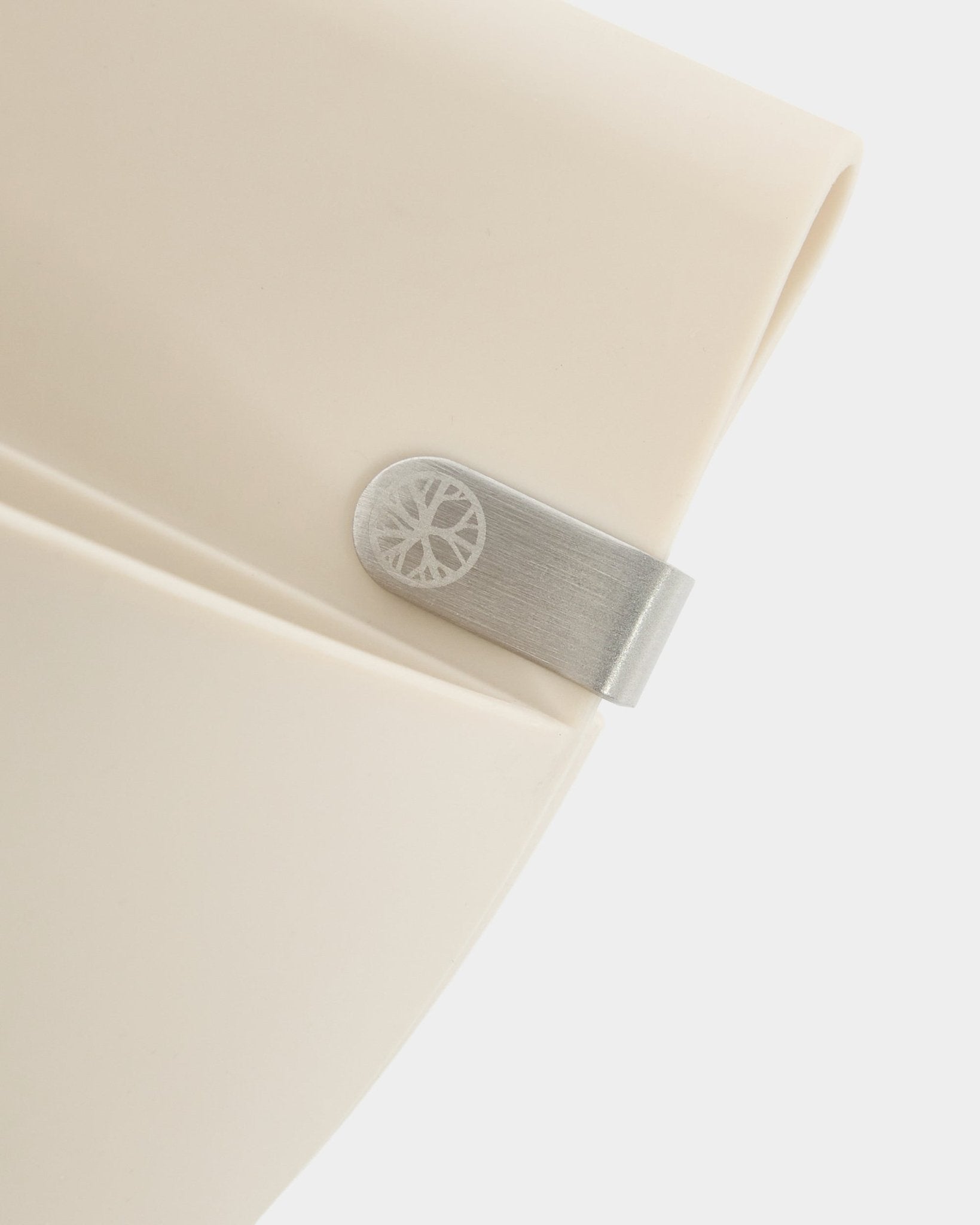 Grande plano de um painel WoodUpp Gro | Soft Pocket / BM2 (4 l) em beige claro, com clipe metálico e detalhe circular gravado, sobre um fundo branco liso.