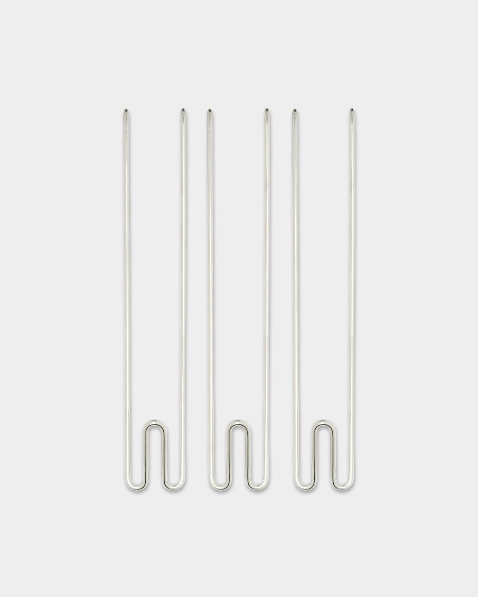 Três acessórios Alva Wire Hook / BM1 da WoodUpp, ganchos compridos em aço inoxidável steel dispostos na vertical sobre um fundo branco liso.