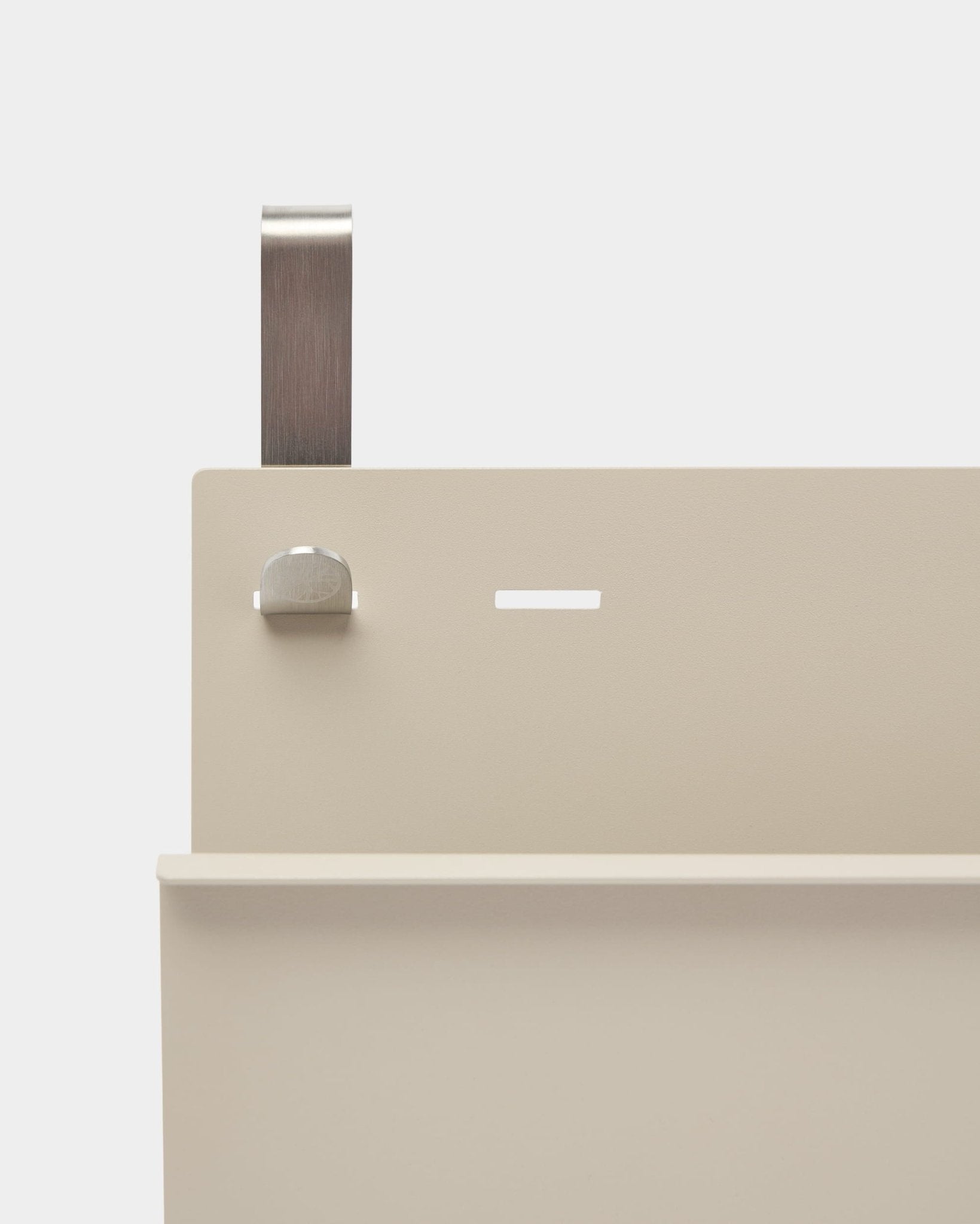Plano aproximado do Nell Magazine Storage da WoodUpp em beige, em steel com revestimento a pó, com prateleira, ranhura, parafuso e pega curva; funciona como separador de ambientes ou suporte para revistas.