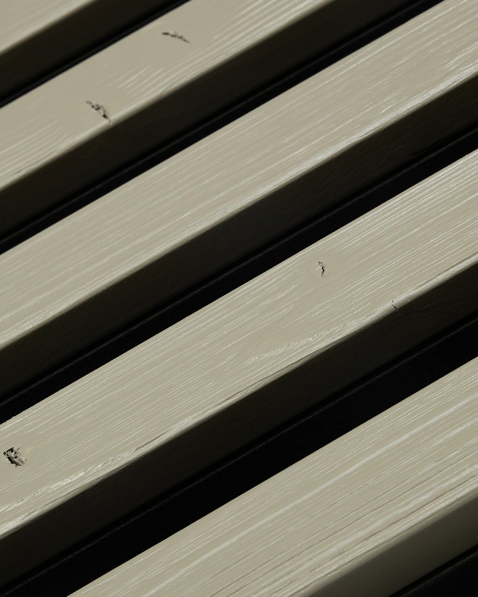 Grande plano do painel de fachada WoodUpp Aluwood grey (240 x 45.1 cm), com formigas small black a rastejar sobre as ripas exteriores.