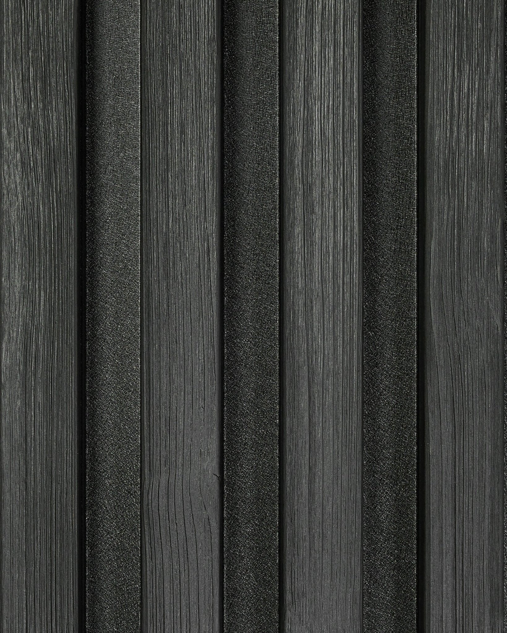 Pormenor de uma amostra do painel de fachada Aluwood Black (45,7 x 27 cm) da WoodUpp, com ripas de textura vertical e um padrão moderno às riscas.