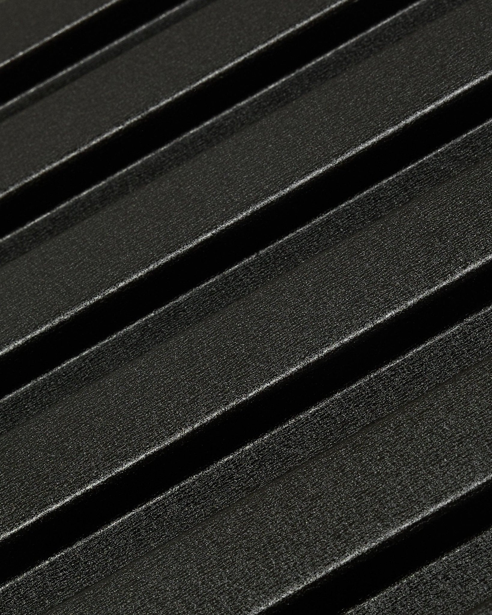 Grande plano do painel de fachada exterior Aluwood da WoodUpp: superfície escura e texturada em alumínio reciclado, com relevos diagonais, medindo 240 x 45,1 cm.
