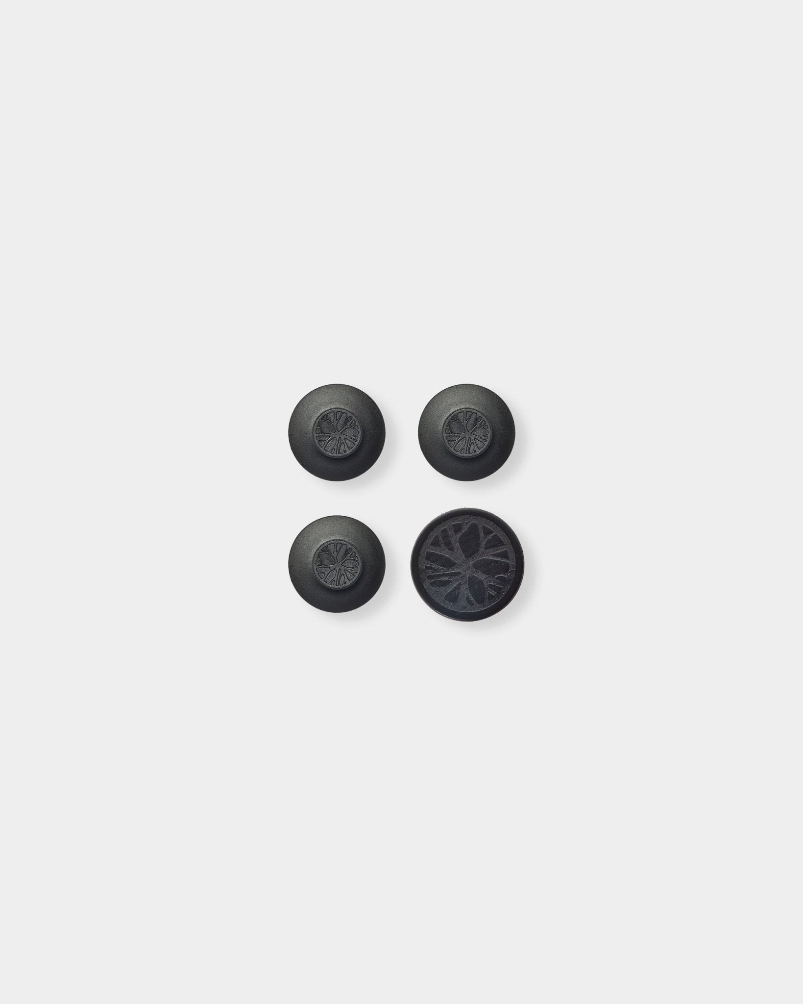 Três black Dupps redondos e uma peça circular com um padrão detalhado de ripas acústicas em madeira, inspirado no Akupanel da Nordic WoodUpp, sobre um fundo cinzento-claro.