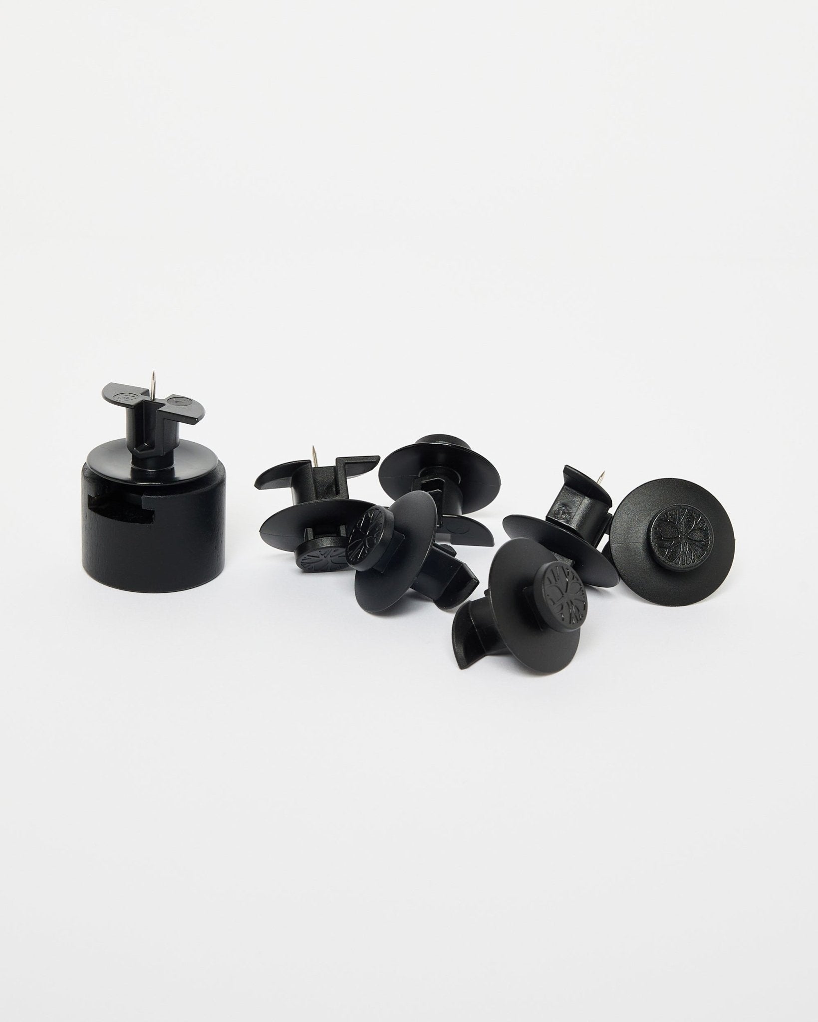 Dupps da WoodUpp: sete fechos de segurança em plástico black, uma ferramenta de instalação e suportes de nylon dispostos sobre um fundo branco liso.
