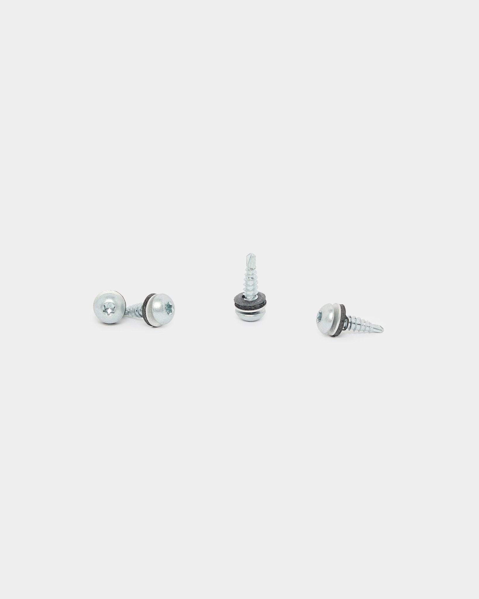 Três parafusos WoodUpp Backside Screws (4.8x19, anilha Ø10, TX20), usados na instalação de Painel acústico, estão dispostos em direções diferentes sobre um fundo branco.