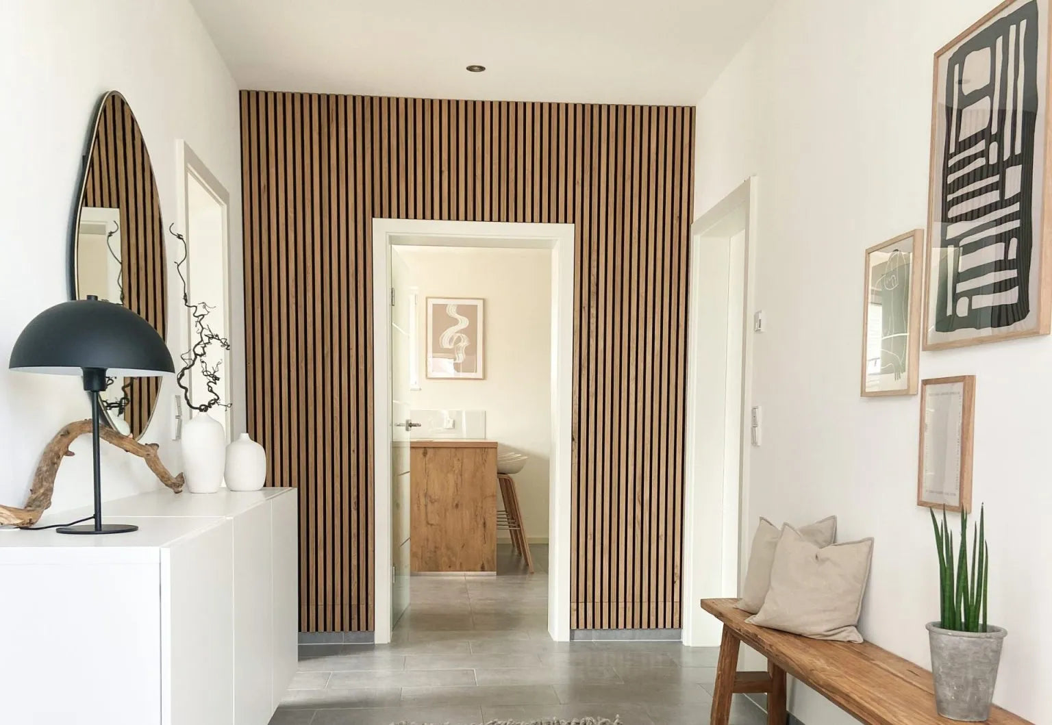 Um corredor moderno com uma parede de destaque acústico de ripas de madeira nórdica Akupanel, paredes brancas, um banco almofadado e decoração minimalista.