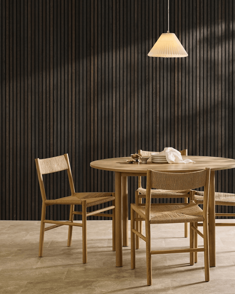 Zona de refeição minimalista com mesa de madeira, cadeiras escandinavas, candeeiro suspenso e um painel ripado acústico WoodUpp Akupanel Rustic Smoked Oak.