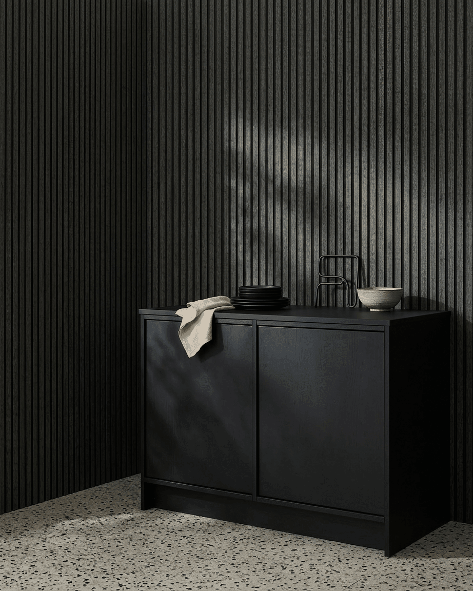 Um armário black ao lado de um painel acústico de madeira WoodUpp Akupanel em Charcoal/Black Felt, com taças e pratos por cima, sobre um chão de terrazzo claro.