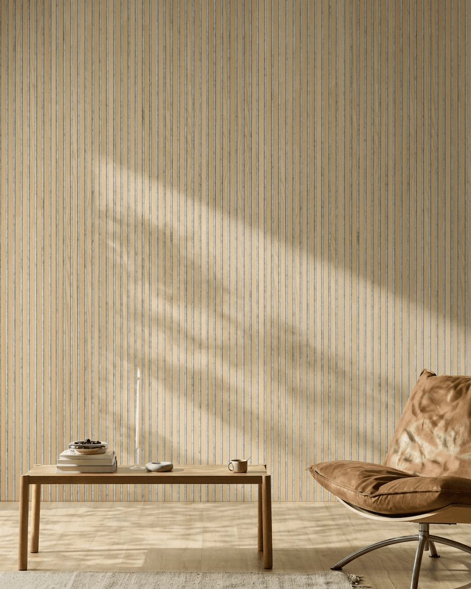 Espaço minimalista com uma cadeira em pele castanha, mesa de madeira e vela. O painel acústico ripado WoodUpp Akupanel Classic Oak acrescenta estilo nórdico e conforto acústico.