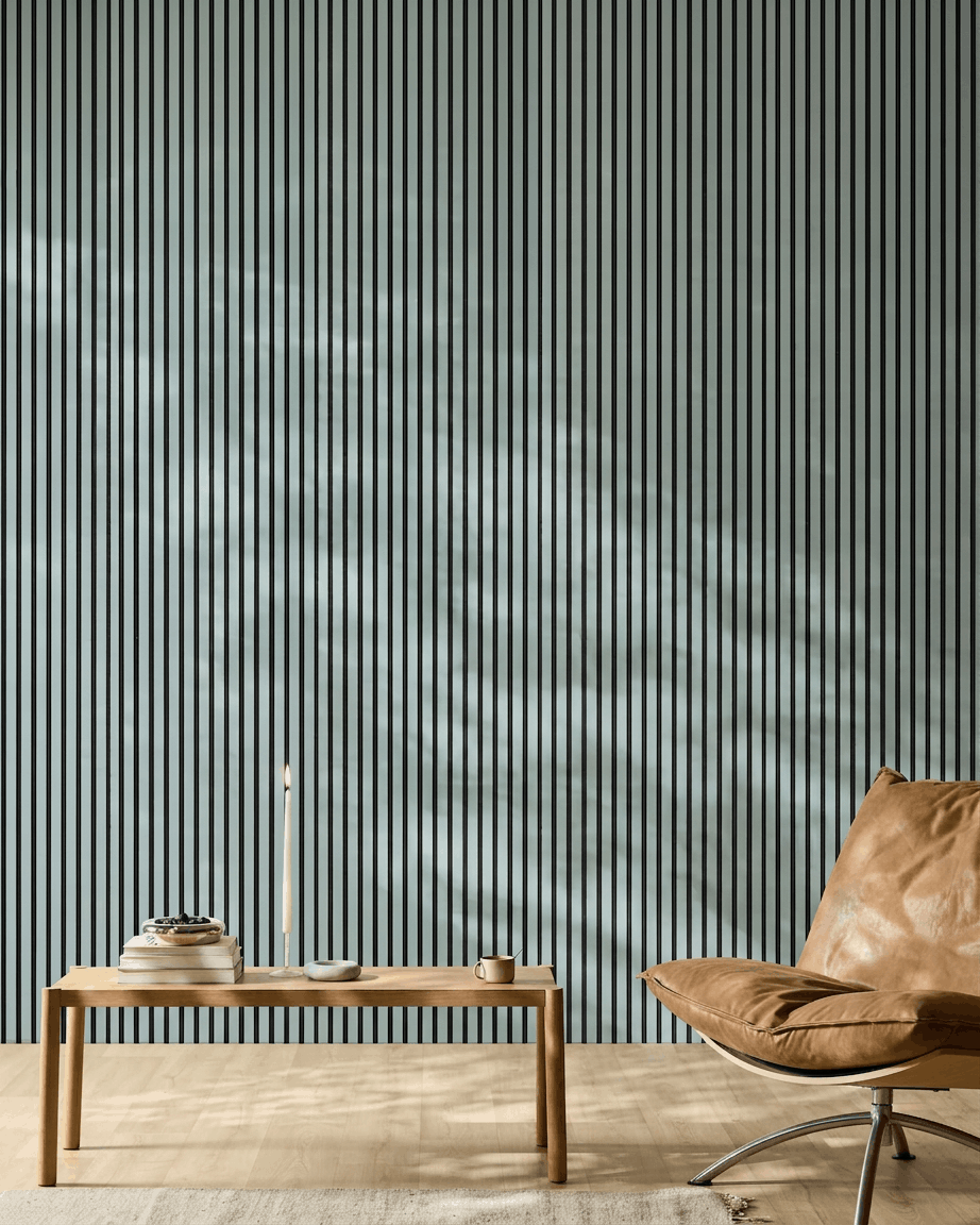 Espaço minimalista com um banco de madeira, livros e uma cadeira de pele brown em frente a um WoodUpp Akupanel Painel acústico na cor Cloud com feltro black.